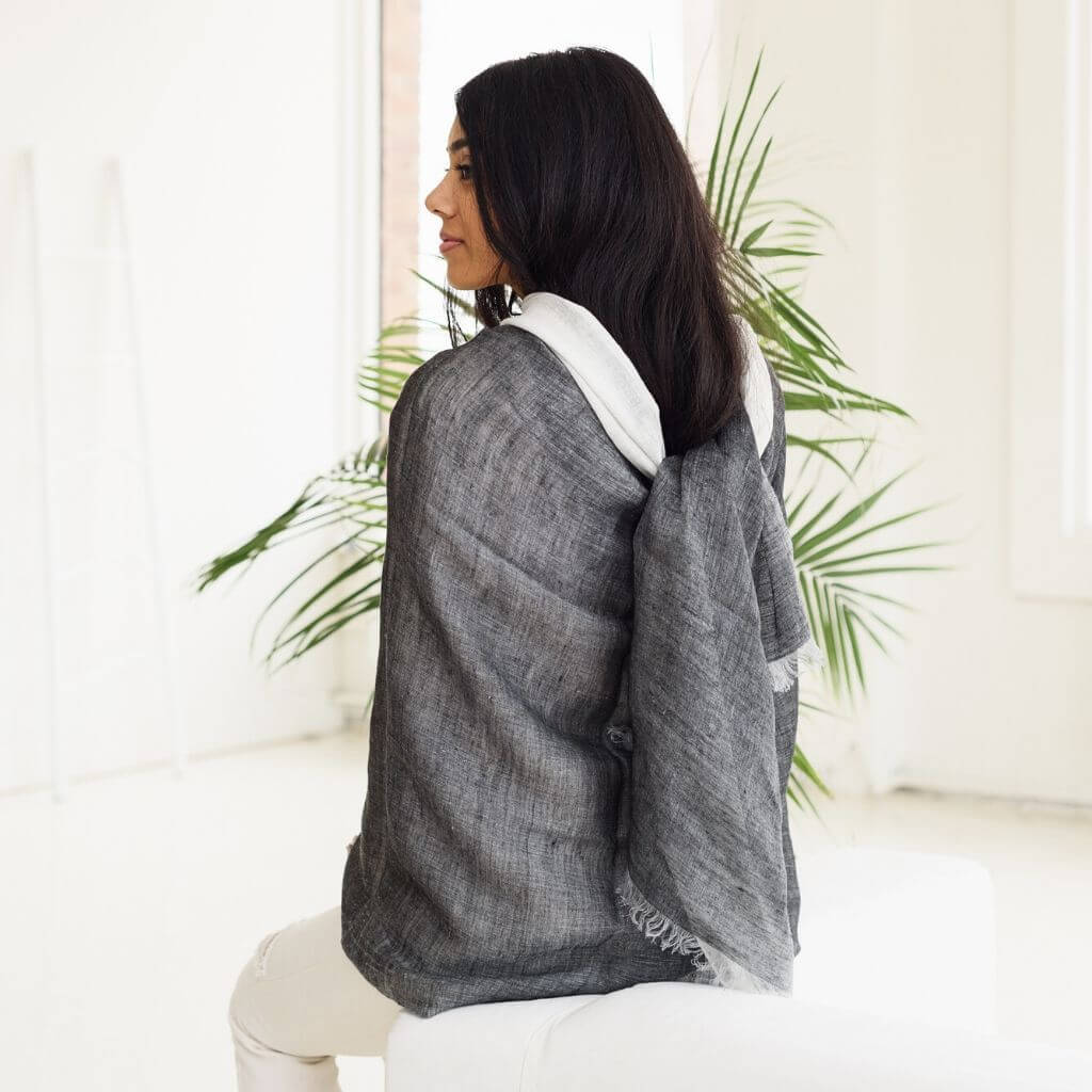 A woman wearing a Granite Black White Ombre Linen Silk Handloom Scarf, showcasing its elegant drape and texture.