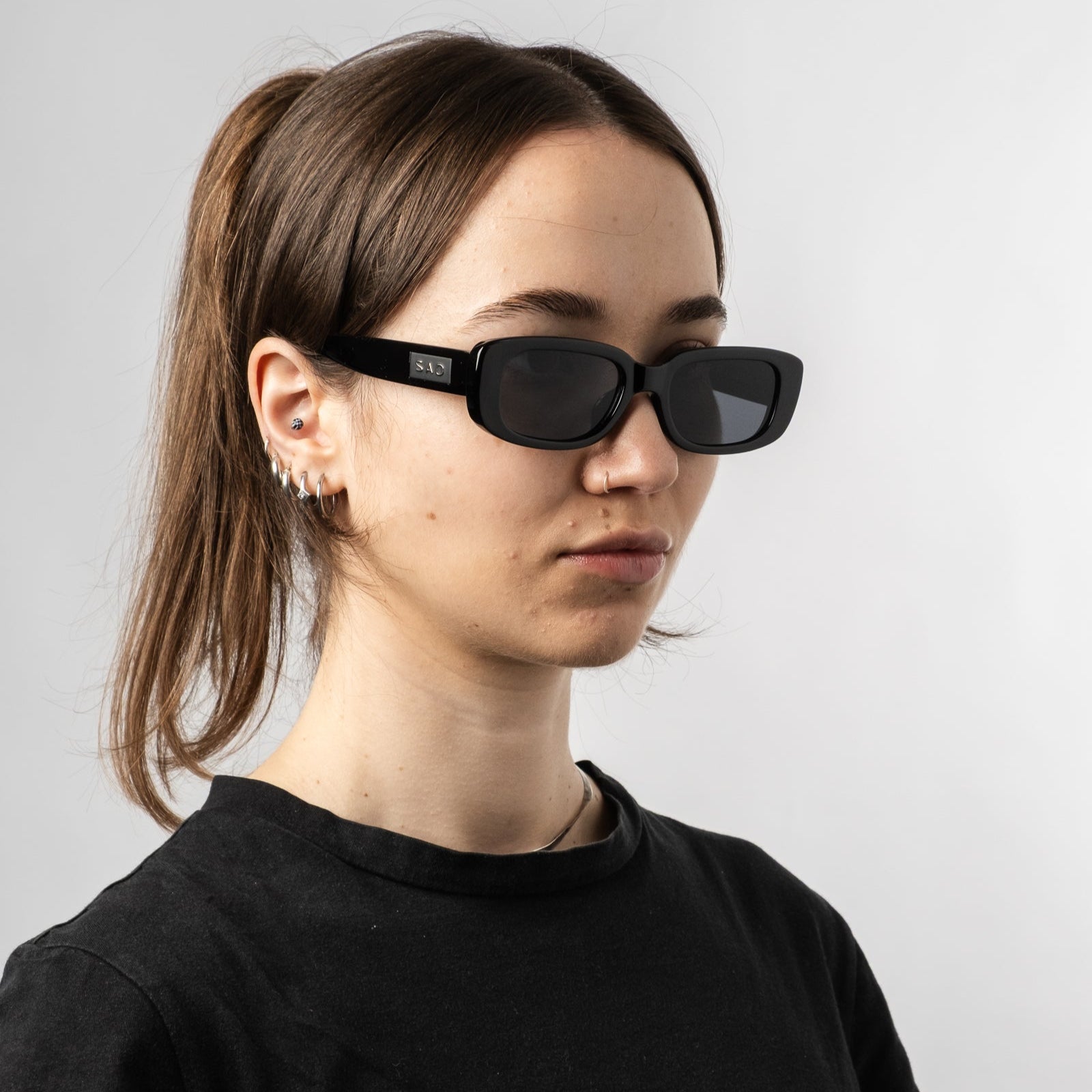 Female wearing Sad Eyewear Bouquet rectangle sunglasses in gloss black with black tinted lenses