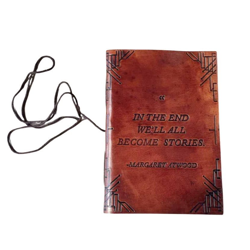 Brown leather-bound book with text and a lanyard on a light background