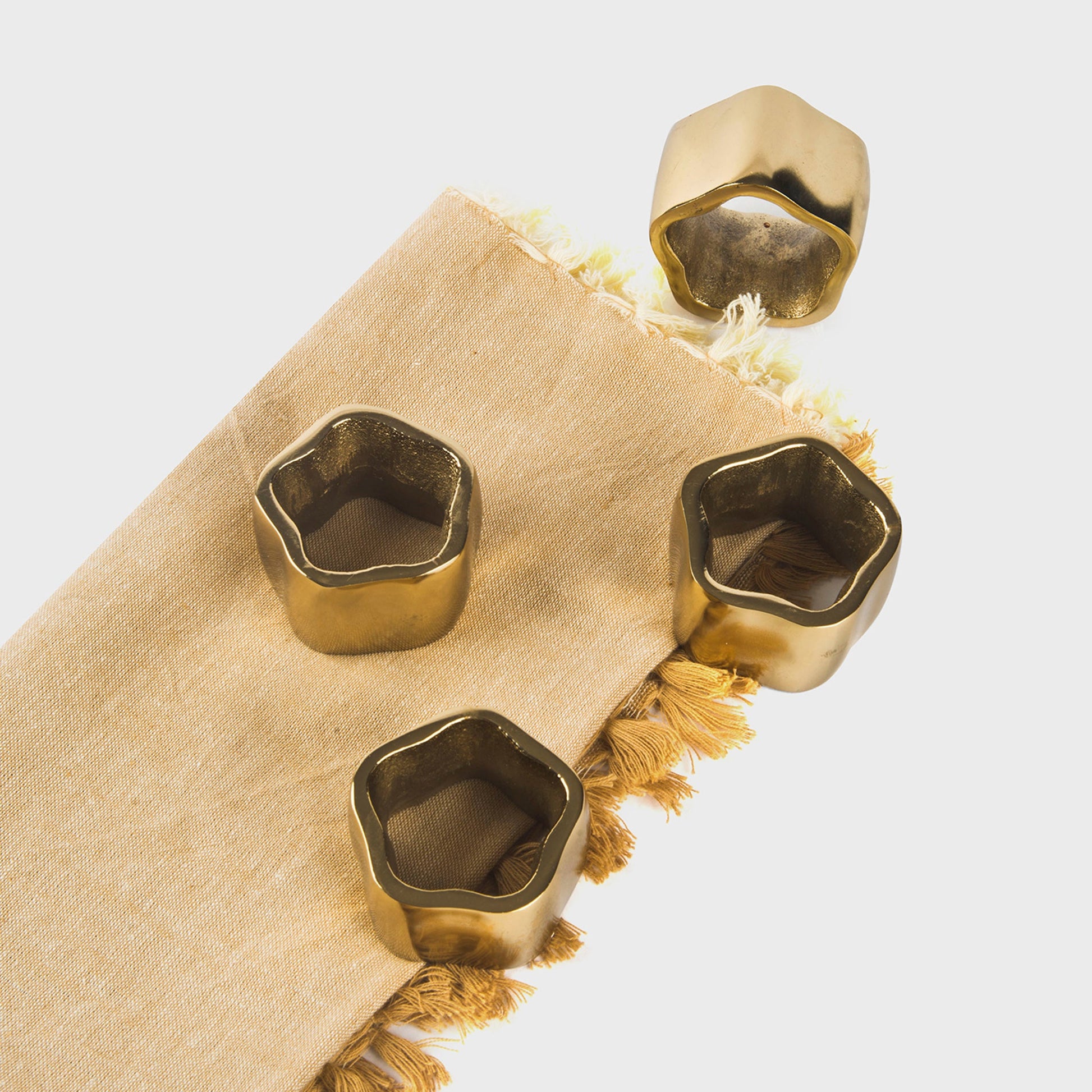 Close-up of a gold-toned sculpted napkin holder highlighting its rich metallic finish and unique geometric edges.