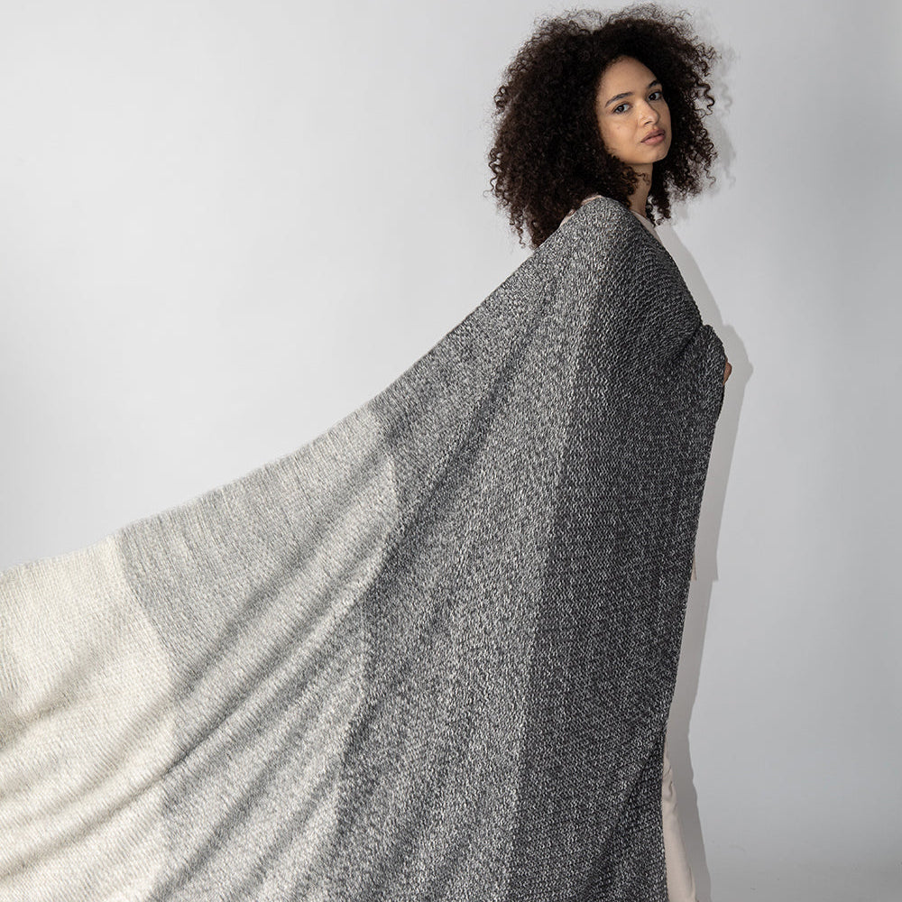 Woman holding a large, gradient cotton textured throw blanket in light and dark gray.