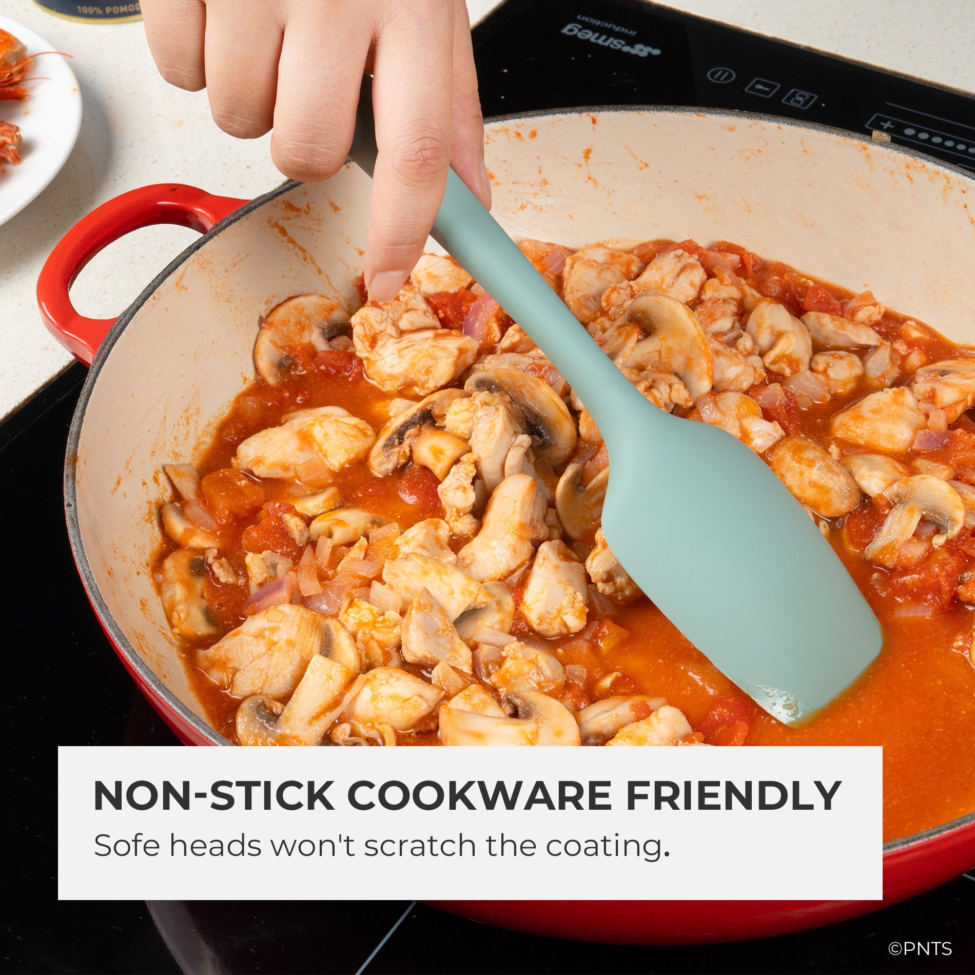 Person stirring a dish of chicken and mushrooms in a red pot with a green spatula, text indicating non-stick cookware compatibility.