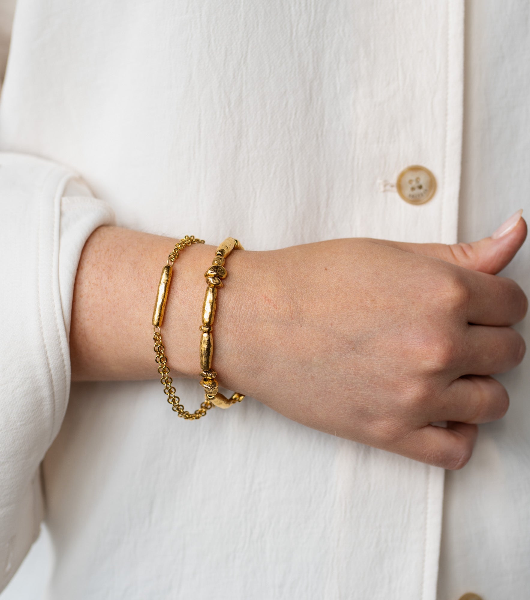 Gold-toned bracelet with sculptural organic beads and a toggle clasp, styled in a circular shape.