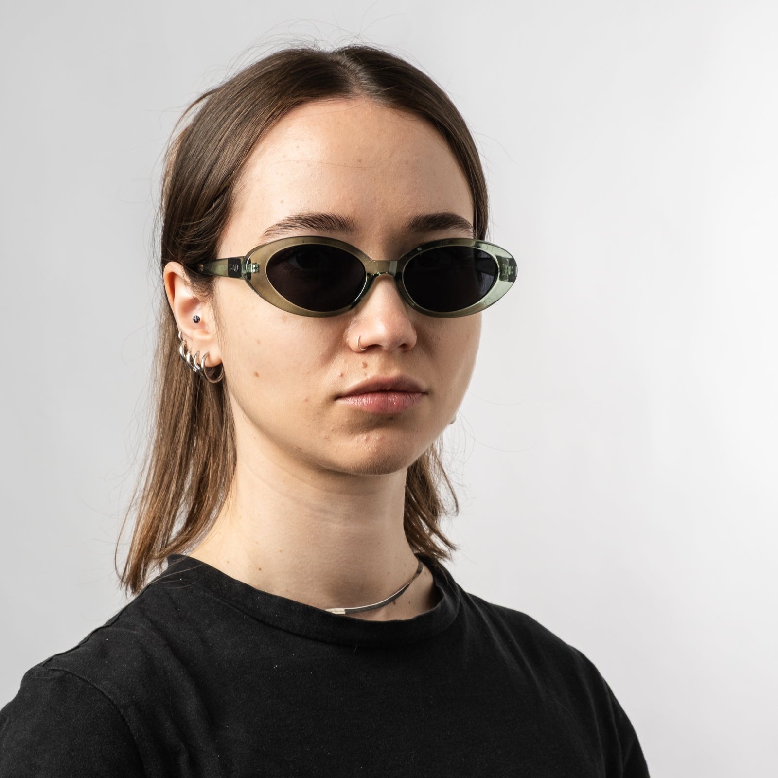 Female wearing Sad Eyewear Bloom oval sunglasses in sea glass green with tinted black lenses