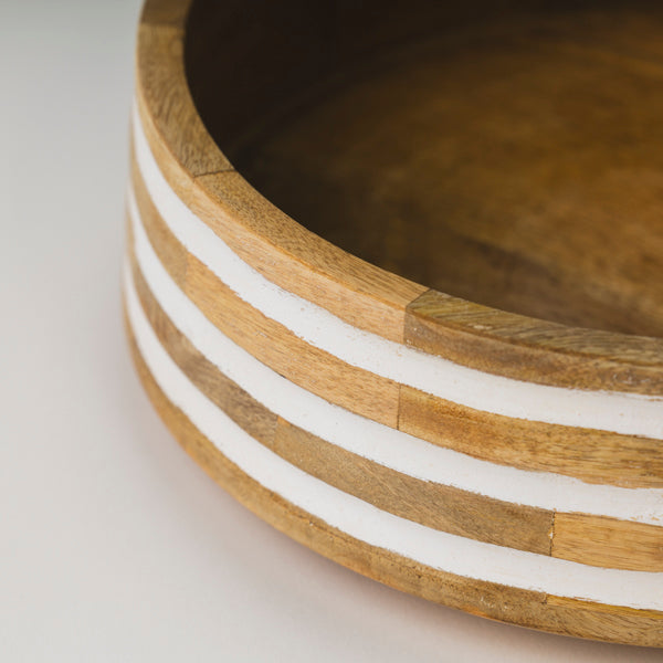 Close-up of the smooth natural mango wood grain and white hand-painted stripes on a decorative bowl.