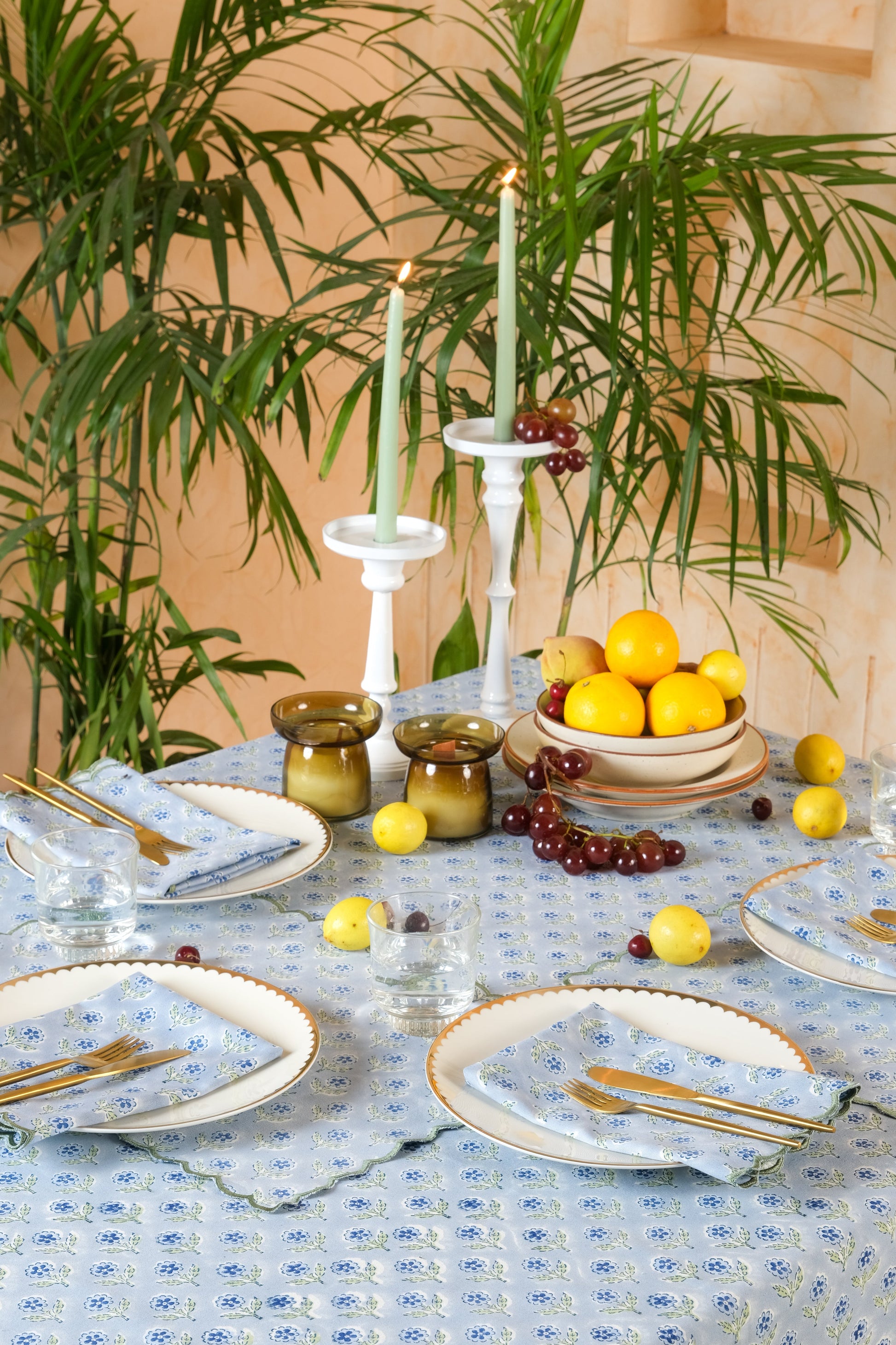 Inner Child blue scallop-edged embroidered blockprint tablecloth with dining setup featuring fruits and candles
