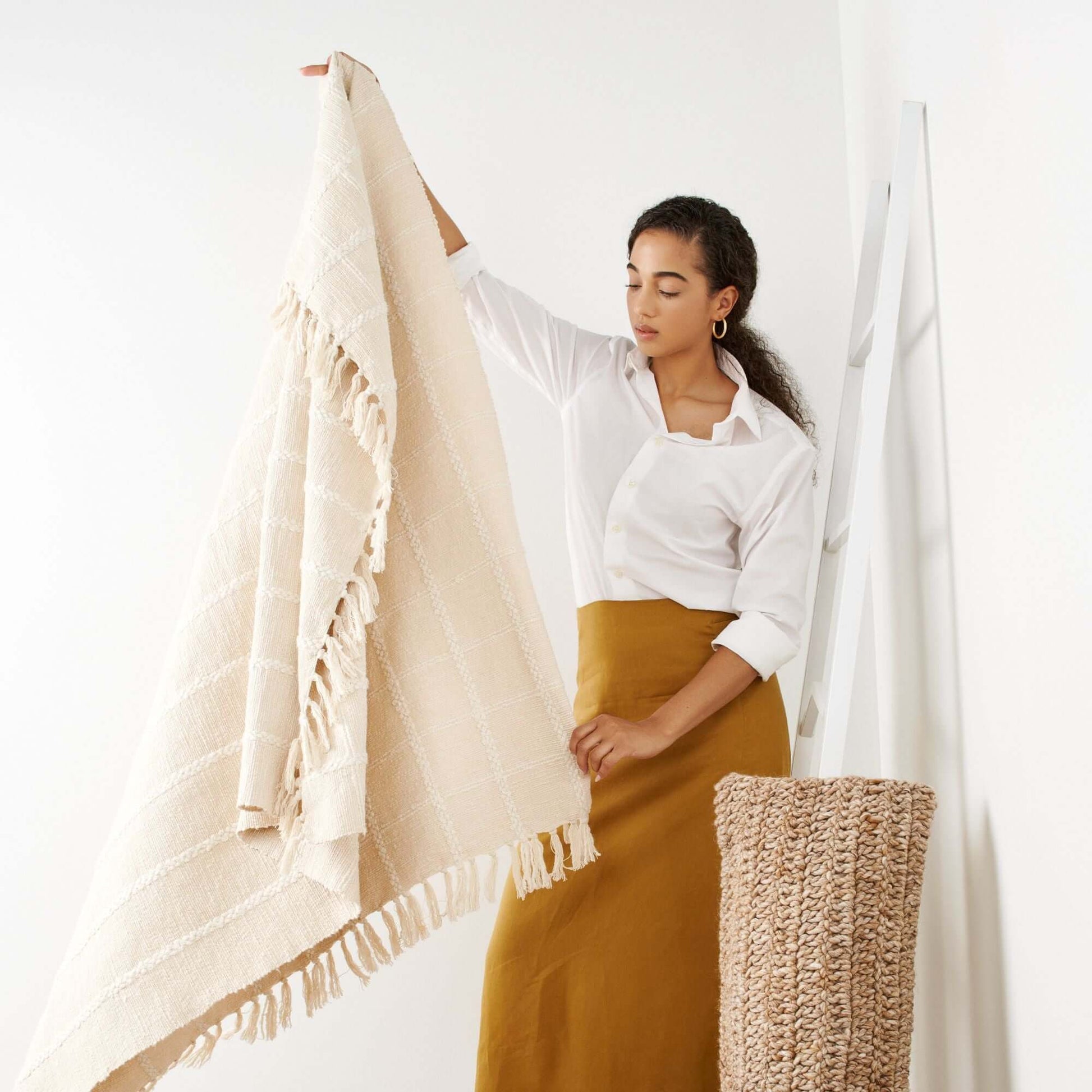 A model showcasing the Sea Shell White Textured Checks Handloom Throw, featuring intricately woven checks and hand-rolled fringes.
