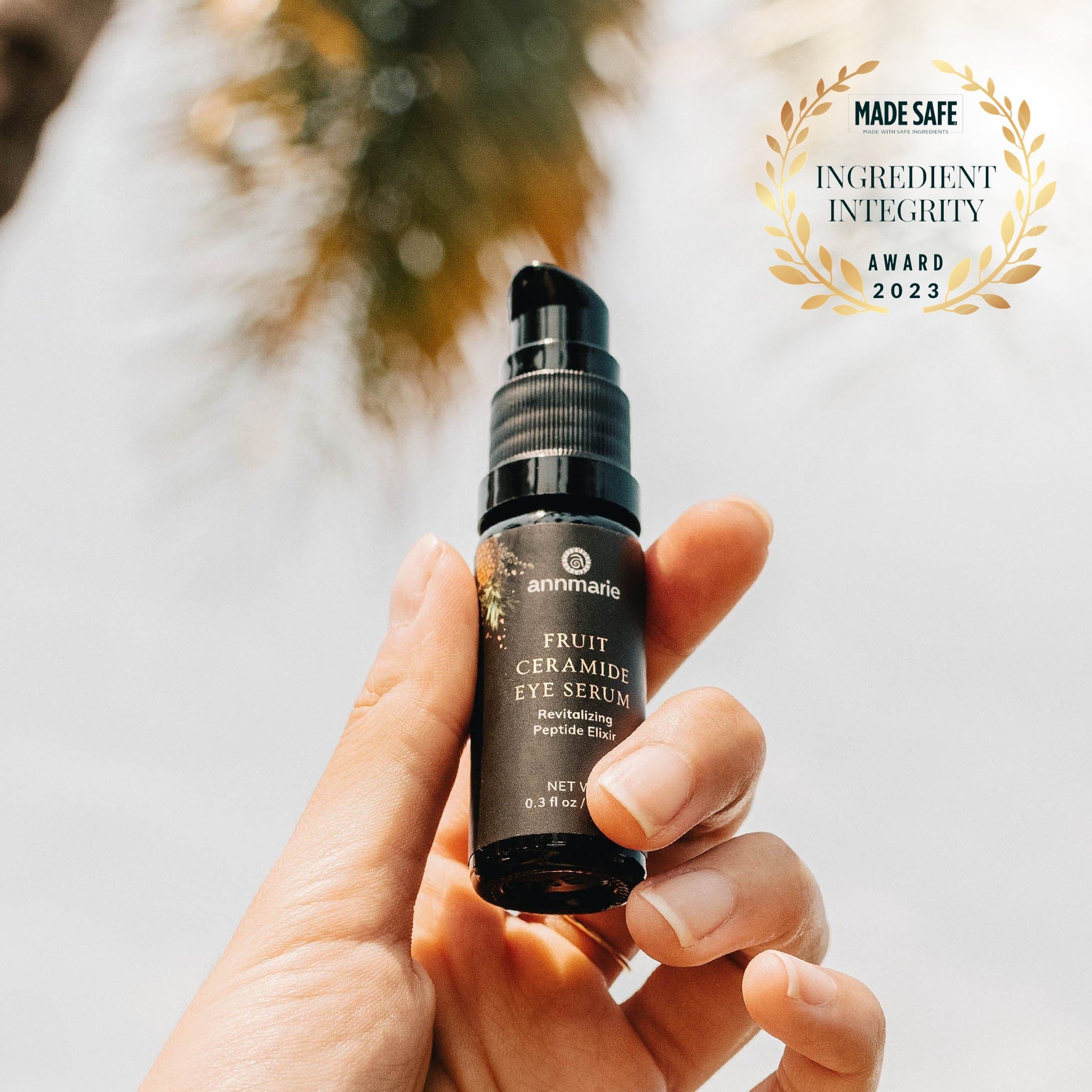 Hand holding a bottle of Annmarie Fruit Ceramide Eye Serum with 'Made Safe Ingredient Integrity Award 2023' badge.