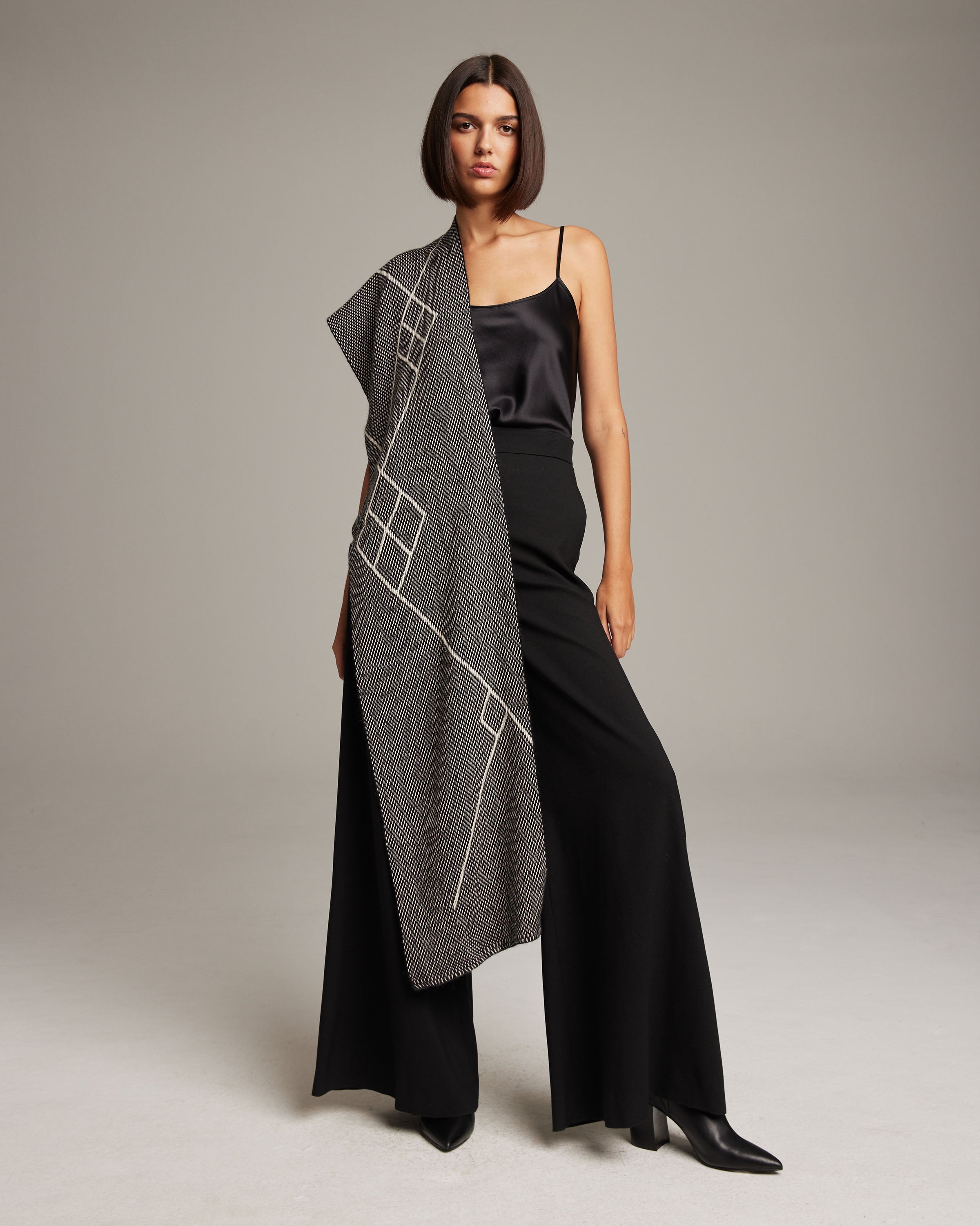 Model wearing Che Scarf in Baby Alpaca, featuring geometric patterns, styled with black outfit.