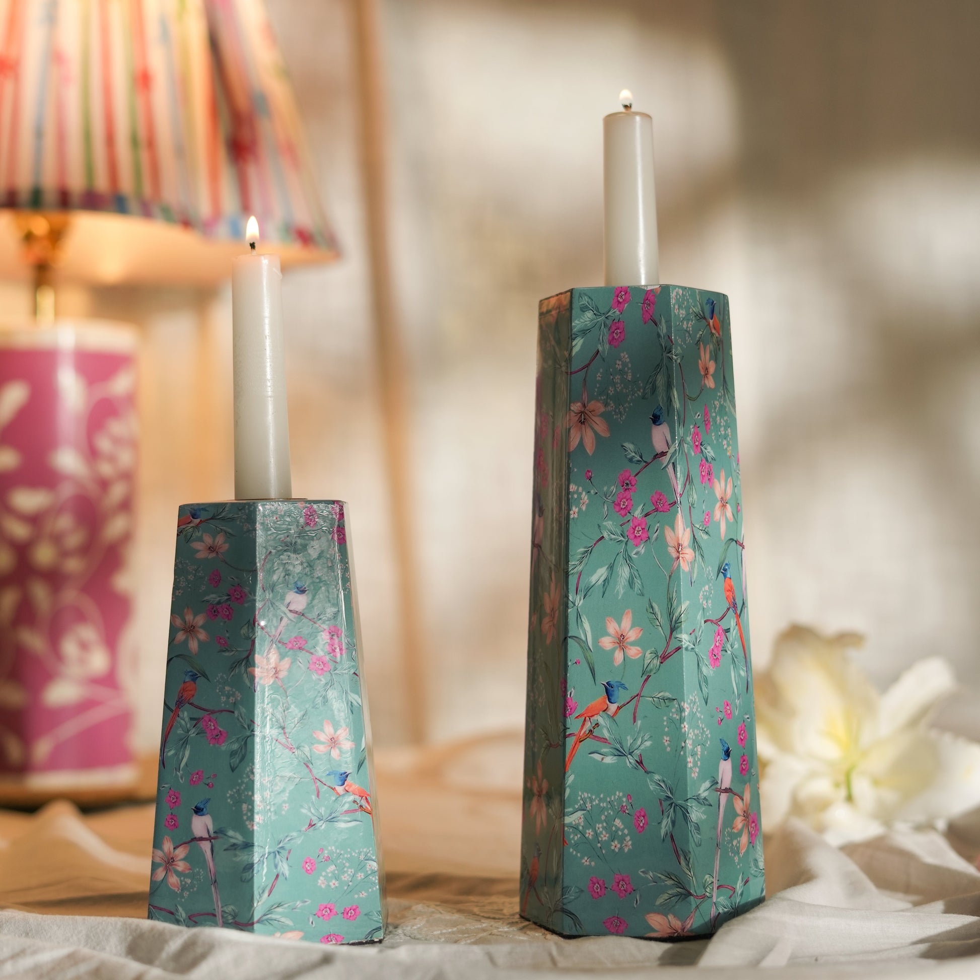 Aqua Flora candleholders styled on a table, casting a warm glow with lit taper candles.
