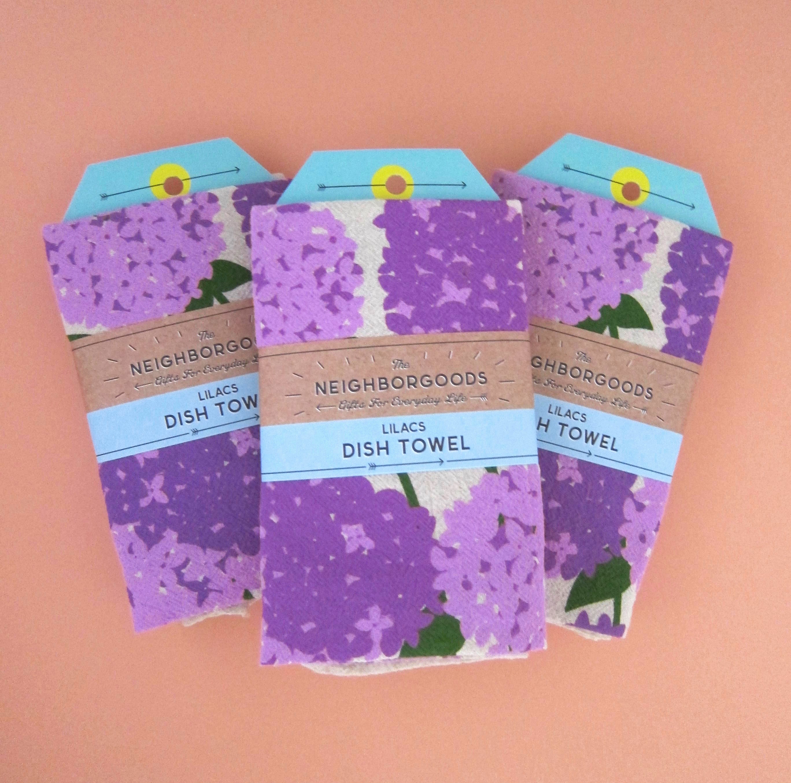 Front view of The Neighborgoods Lilacs dish towel in a ready-to-gift sleeve.