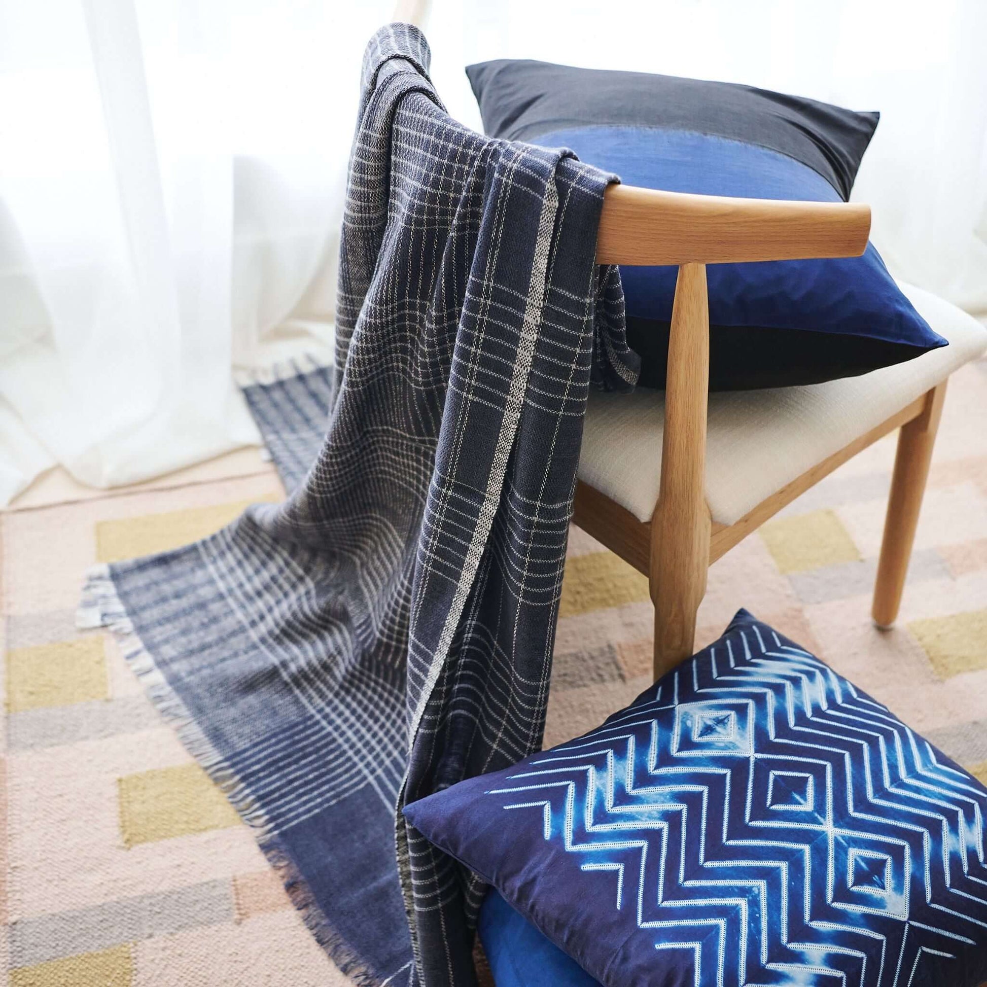 Alloy Dark Blue Stripes Pattern Soft Merino Linen Handloom Throw draped over a modern chair with decorative pillows.