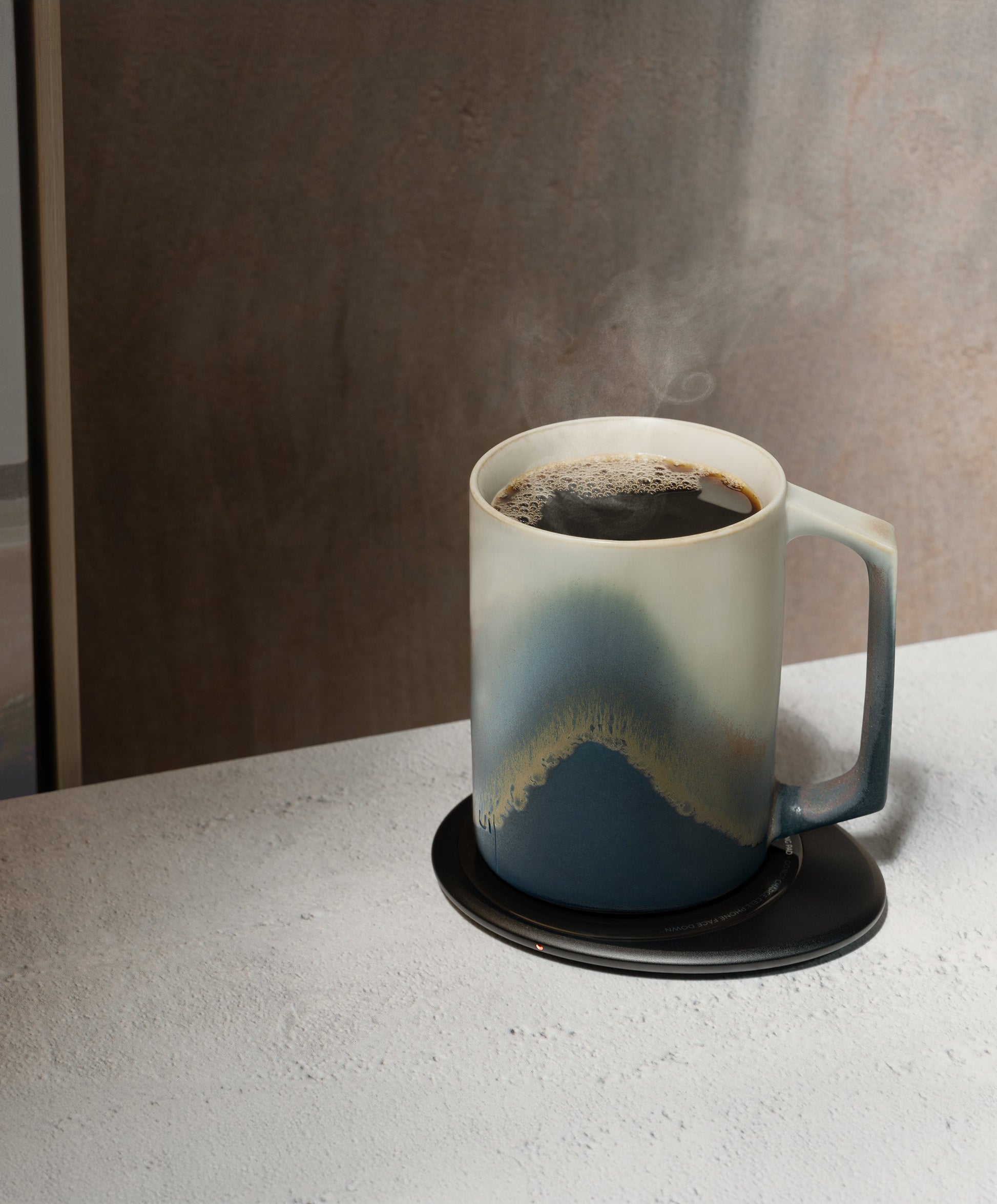 Ui Artist Collection Self-Heating Ceramic Mug 12 fl oz / 355 mL in Arctic Radiance with lid angled top-side view on Ohom Charging Pad 3