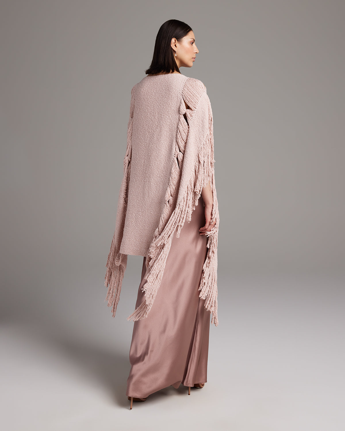 Model wearing a pink Lace Fringe Manta over a long satin dress, showcasing the fringe detail.