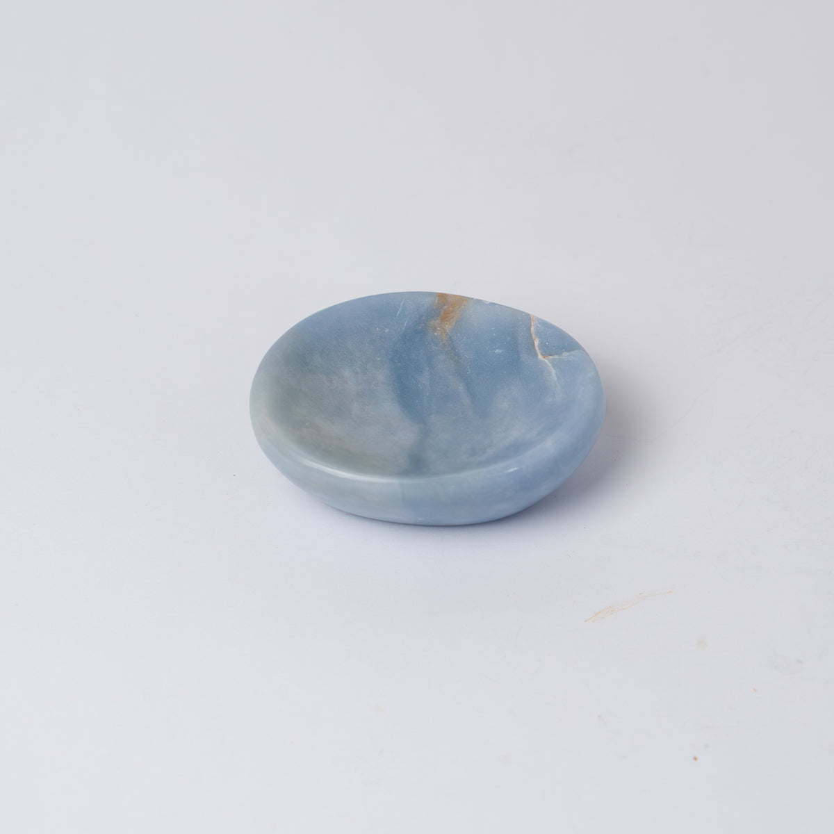 Angled view of the blue angelite gemstone catch-all emphasizing its smooth carved texture on a white background.