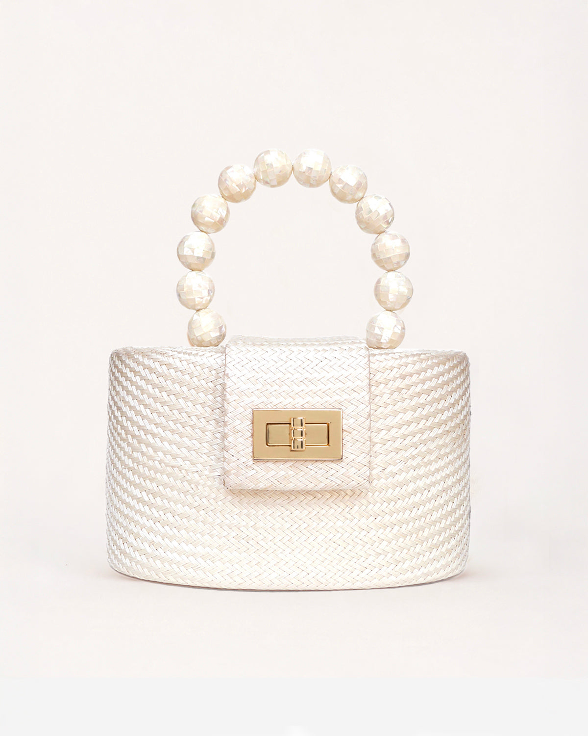 A small structured handbag with a textured cream woven body, a top handle made of mother of pearl beads, and a gold-tone clasp on the front flap, photographed against a clean off-white background.