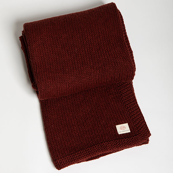 Folded sagria red organic cotton throw with a Pink Lemonade brand label on a light gray background.