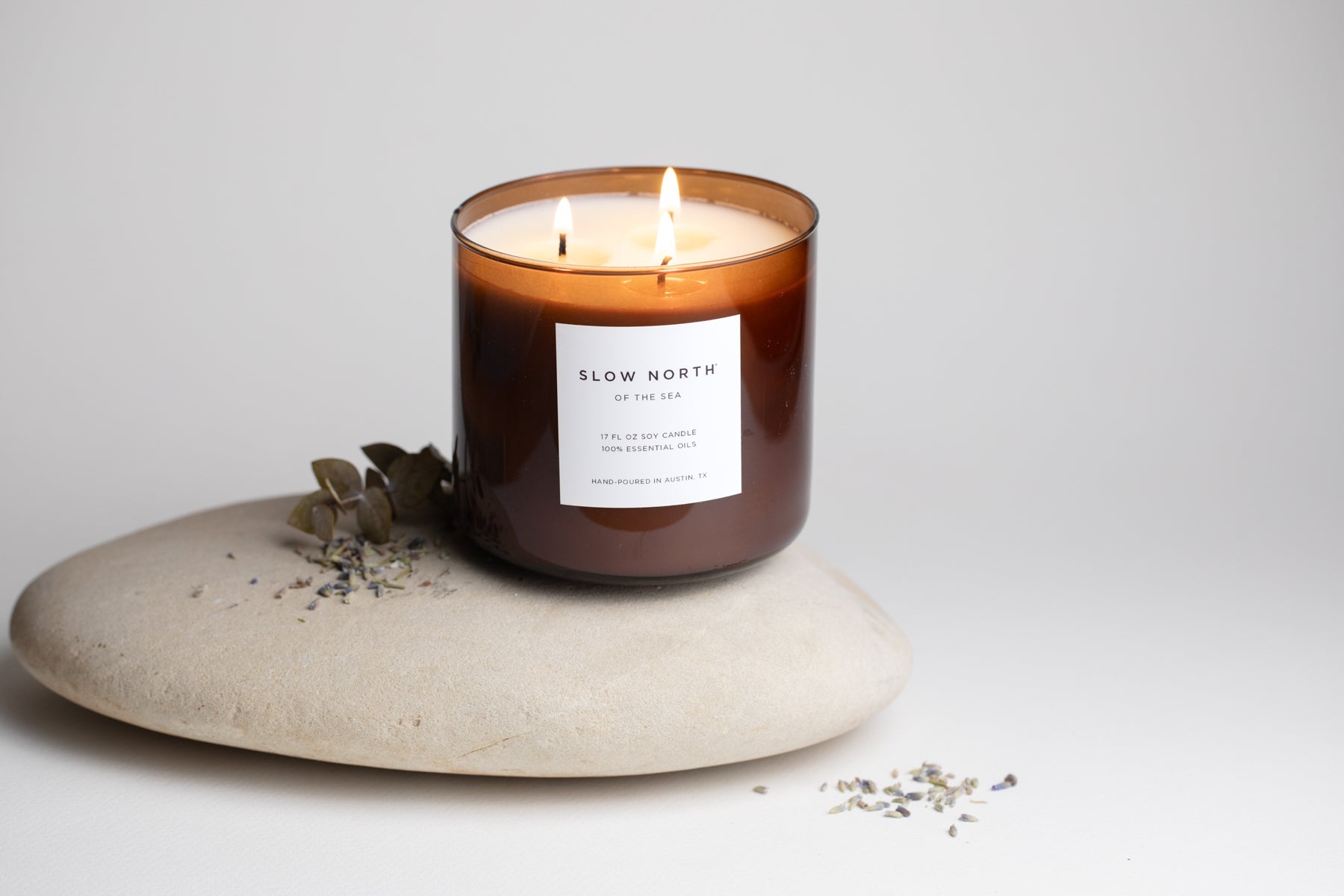 Candle labeled 'Slow North' on a stone surface with a light background