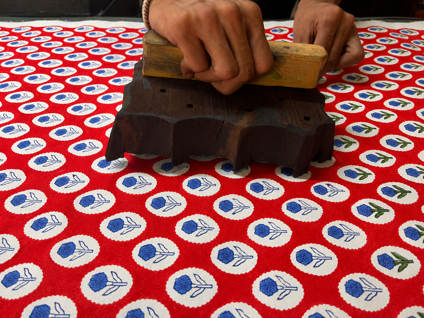 Artisan hand block printing a red floral textile