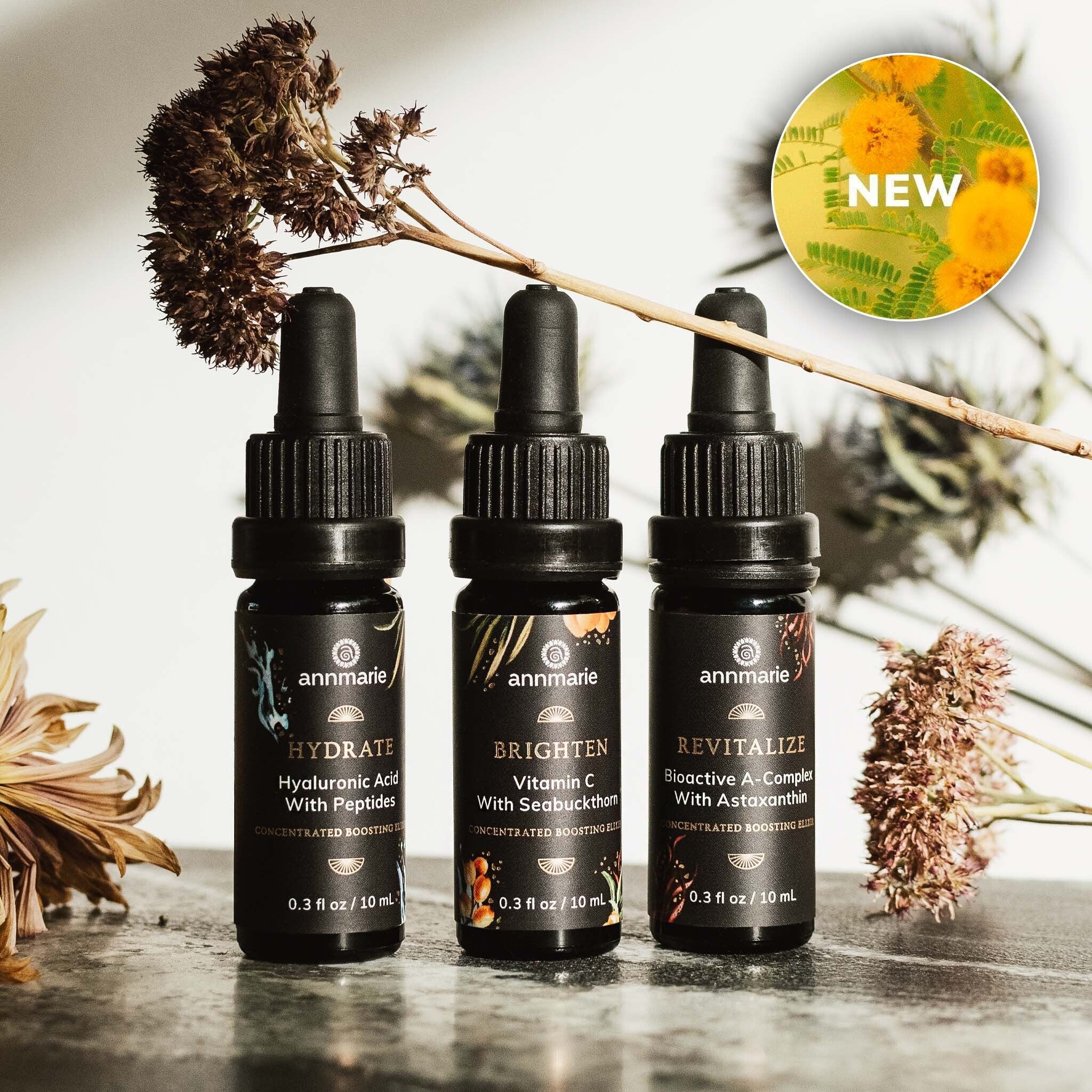 Concentrated boosting elixirs—Hydrate, Brighten, and Revitalize—shown in dropper bottles with dried botanical stems and a “New” badge.