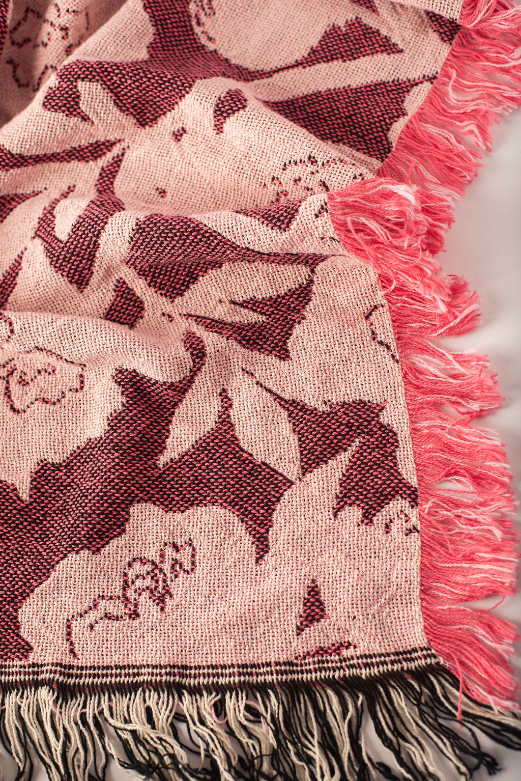 Close-up of Addy Mulberry pink and cream floral woven cotton throw with fringe
