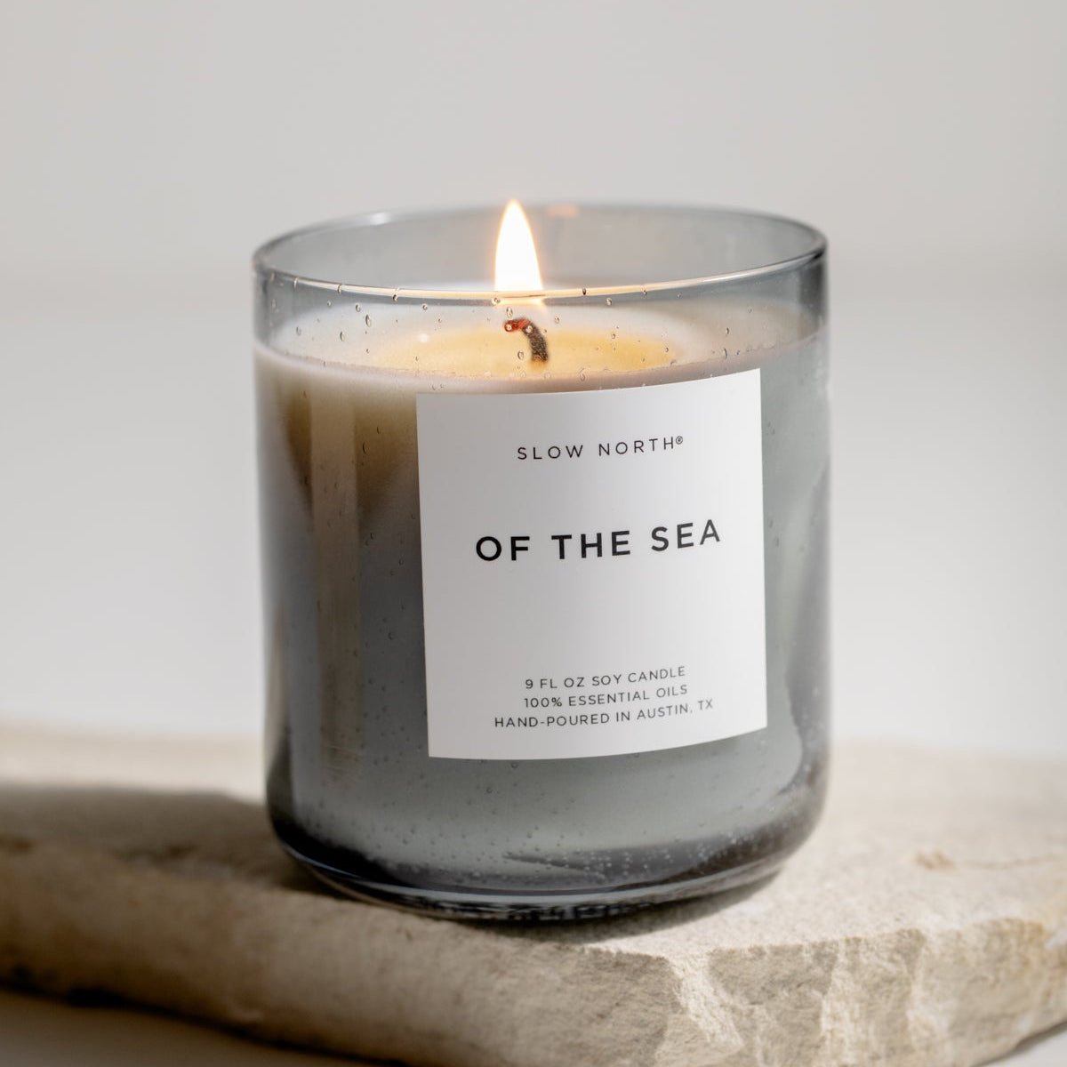 Candle labeled 'Of the Sea' by Slow Nordik on a stone surface with a neutral background