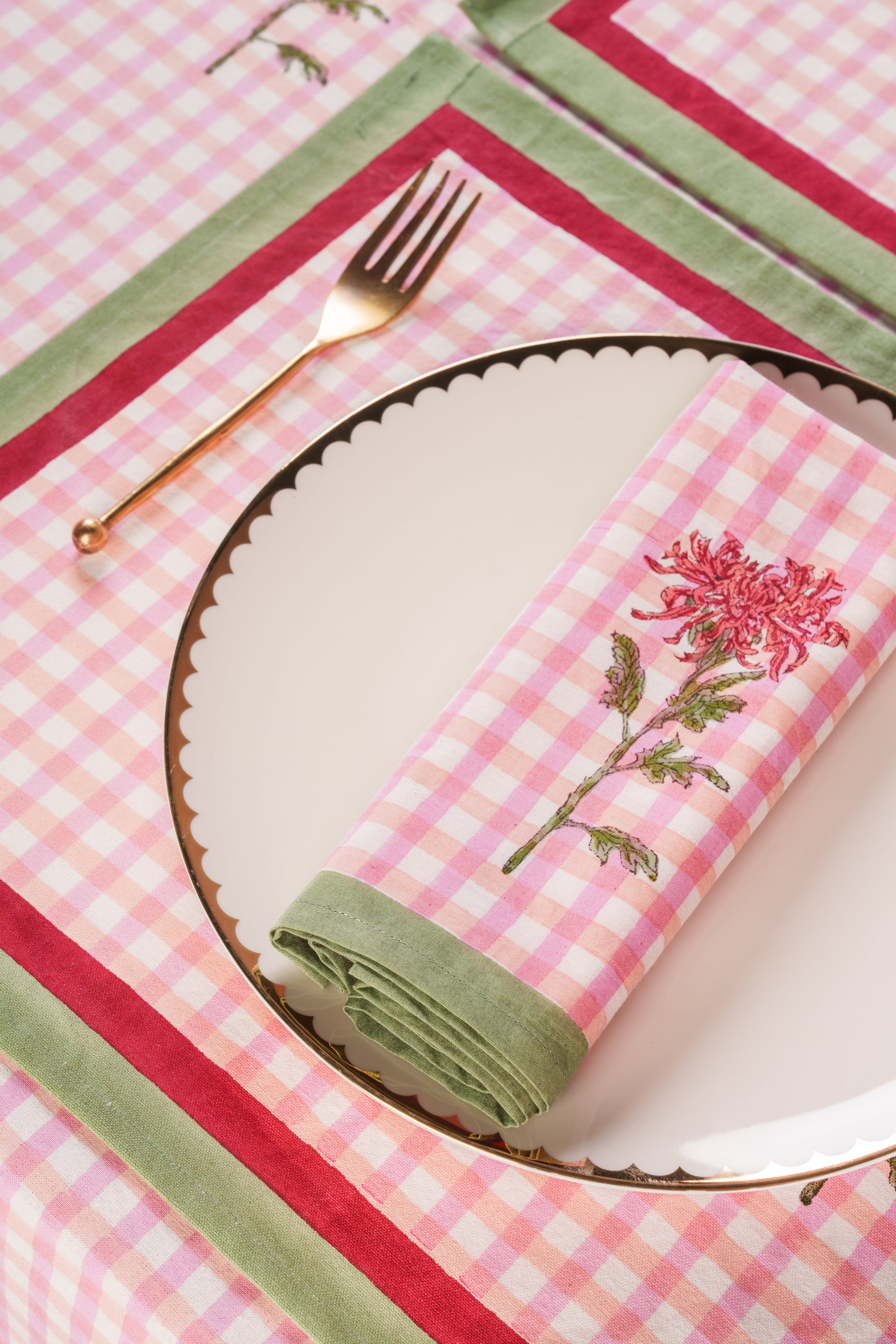 Pink gingham dahlia napkin folded on plate with gold fork by Inner Child