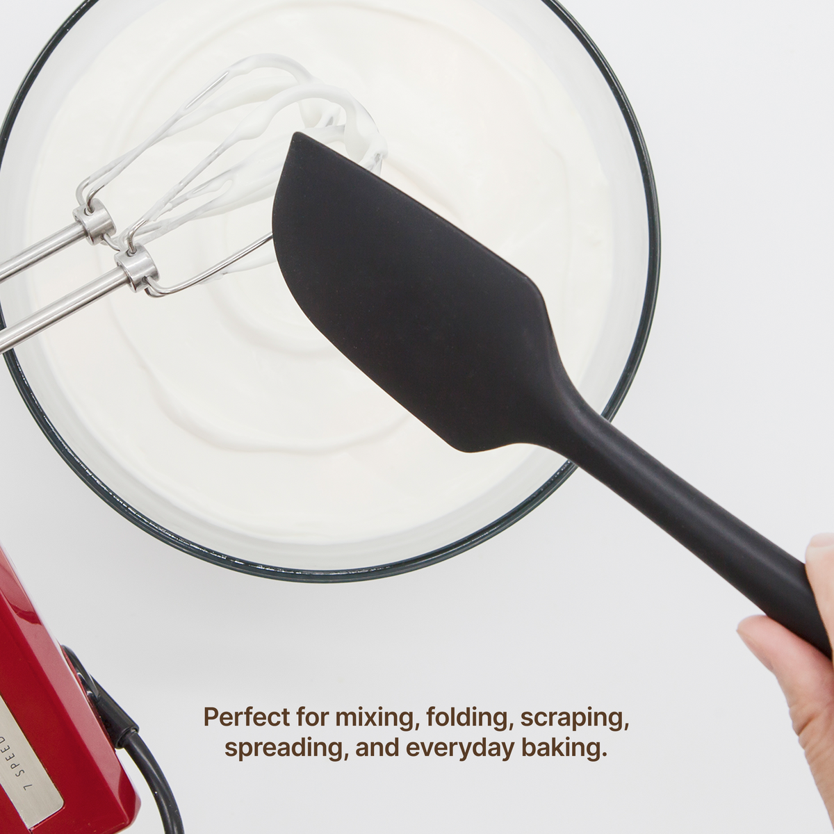 Hand using an Elihome Classic silicone spatula in Black to fold whipped cream in a mixing bowl, perfect for mixing, folding, scraping, spreading and everyday baking
