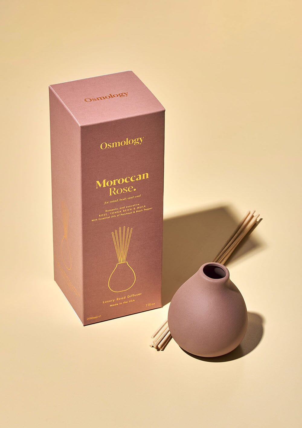 Osmology Moroccan Rose dusty pink clay diffuser with reeds next to product packaging on a white background