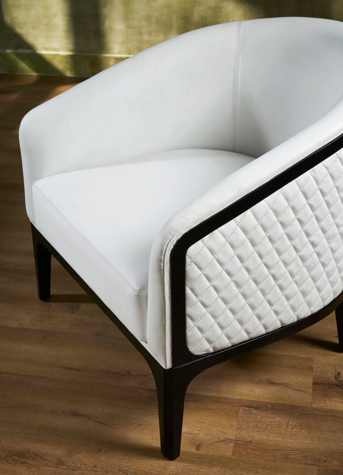 FN-5204-343329_6|Close-up angle of white leather armchair with quilted side and dark wood frame, highlighting luxury leather furniture details.
