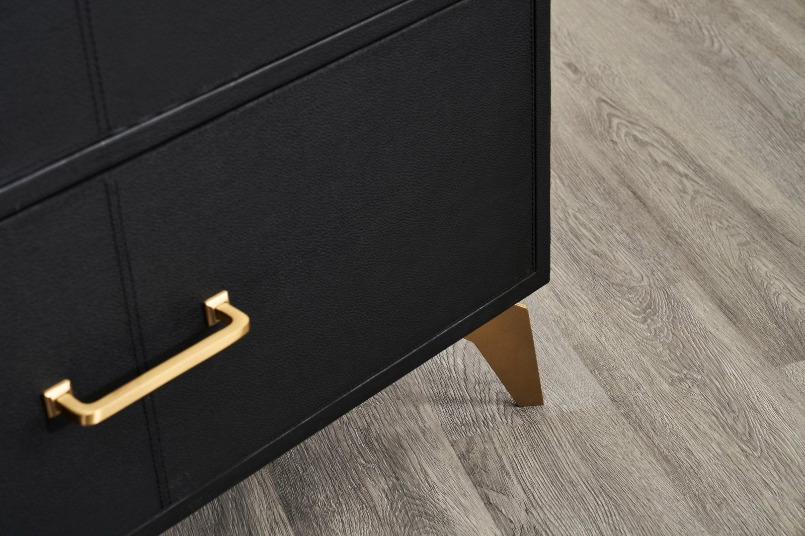 FN-5200-642033_7|Detail of the elegant gold tapered leg on a black leather dresser, emphasizing the sturdy and luxurious design.