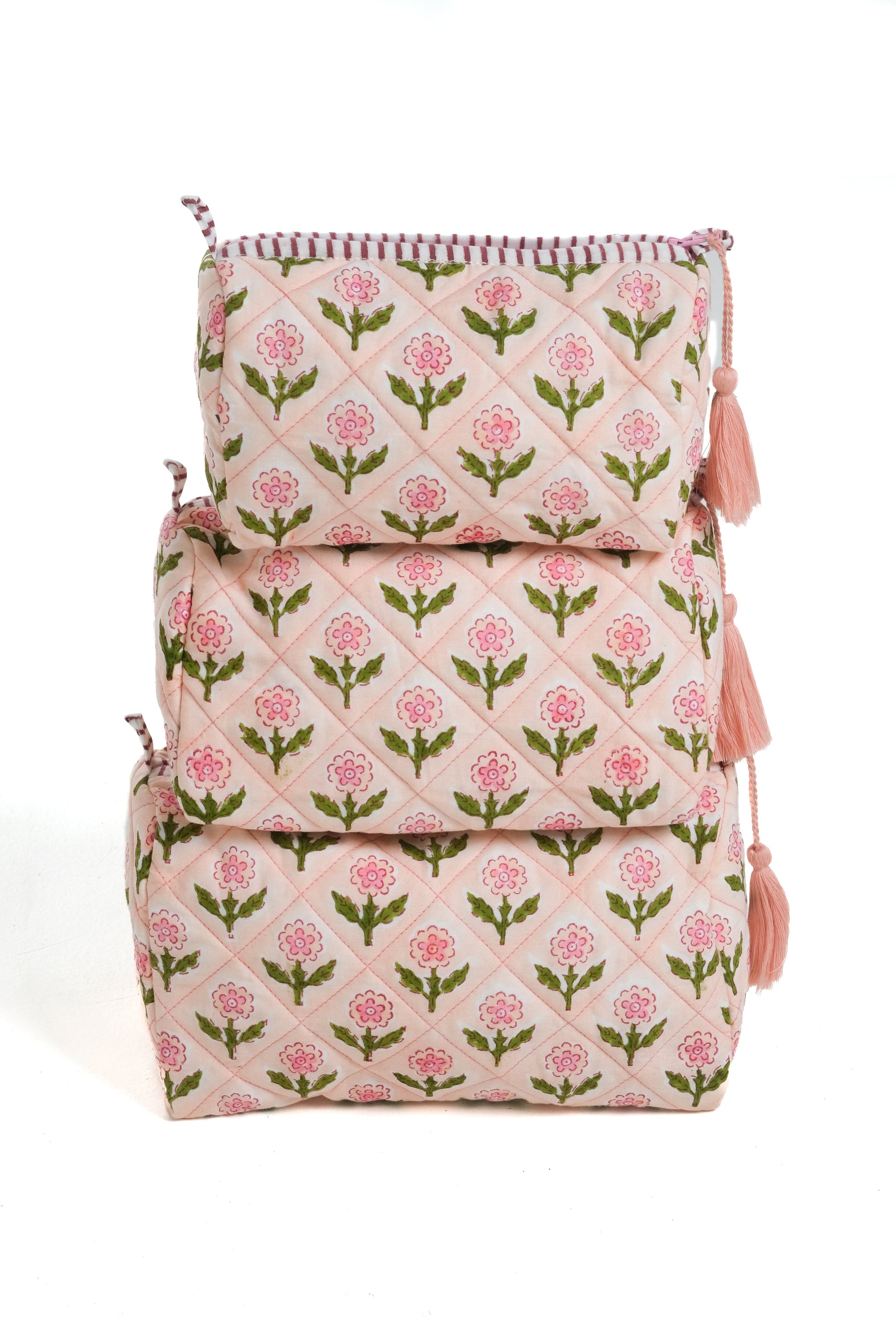 Pink blockprint makeup bags stacked with floral patterns and tassels