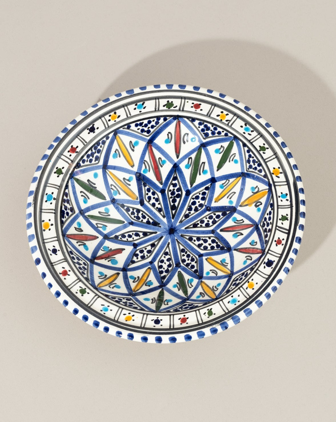 A ceramic decorative plate with a hand-painted geometric pattern predominantly in blue and white colors.