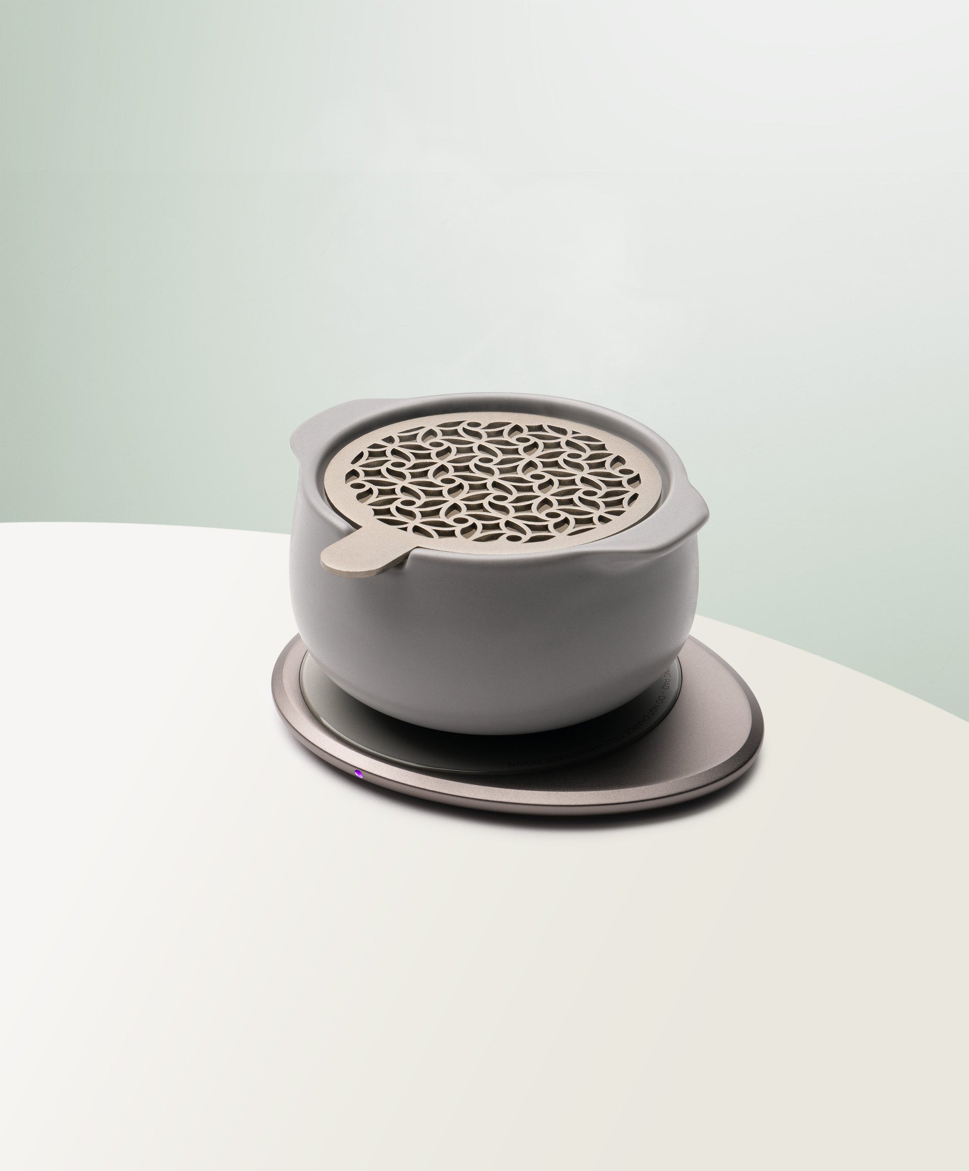 Jun Self-Heating Ceramic Diffuser 5 fl oz / 150 mL with lid in Soft Gray angled view on Ohom Pad 3