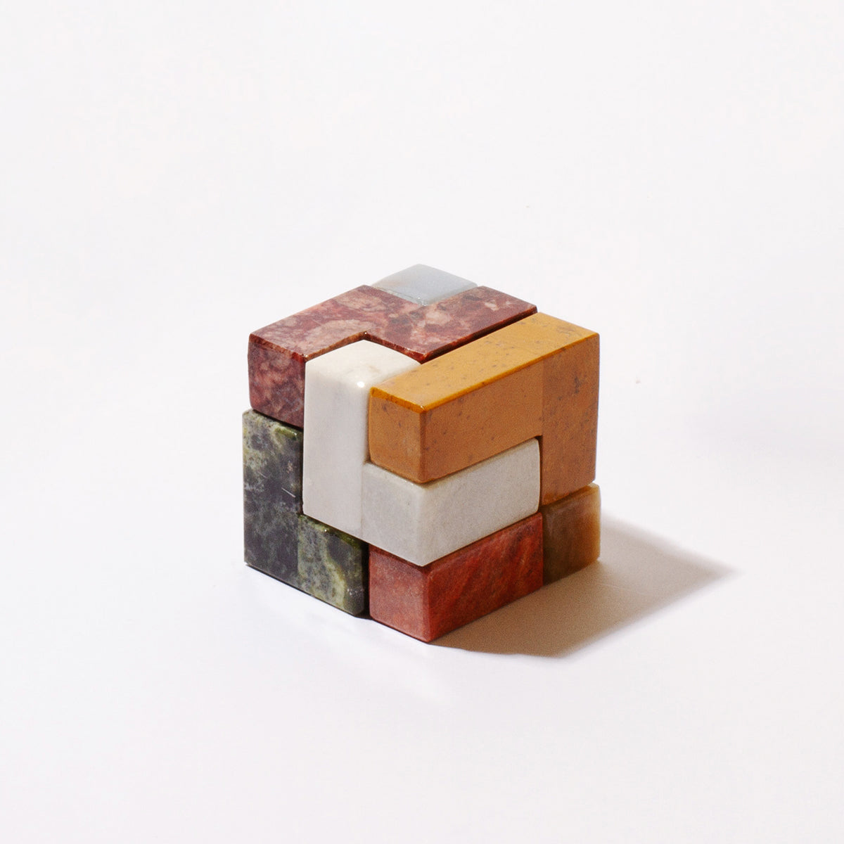 Close-up view of the natural Andean stone Soma cube, highlighting the rich mineral veins and smooth carved finish against a seamless white backdrop.