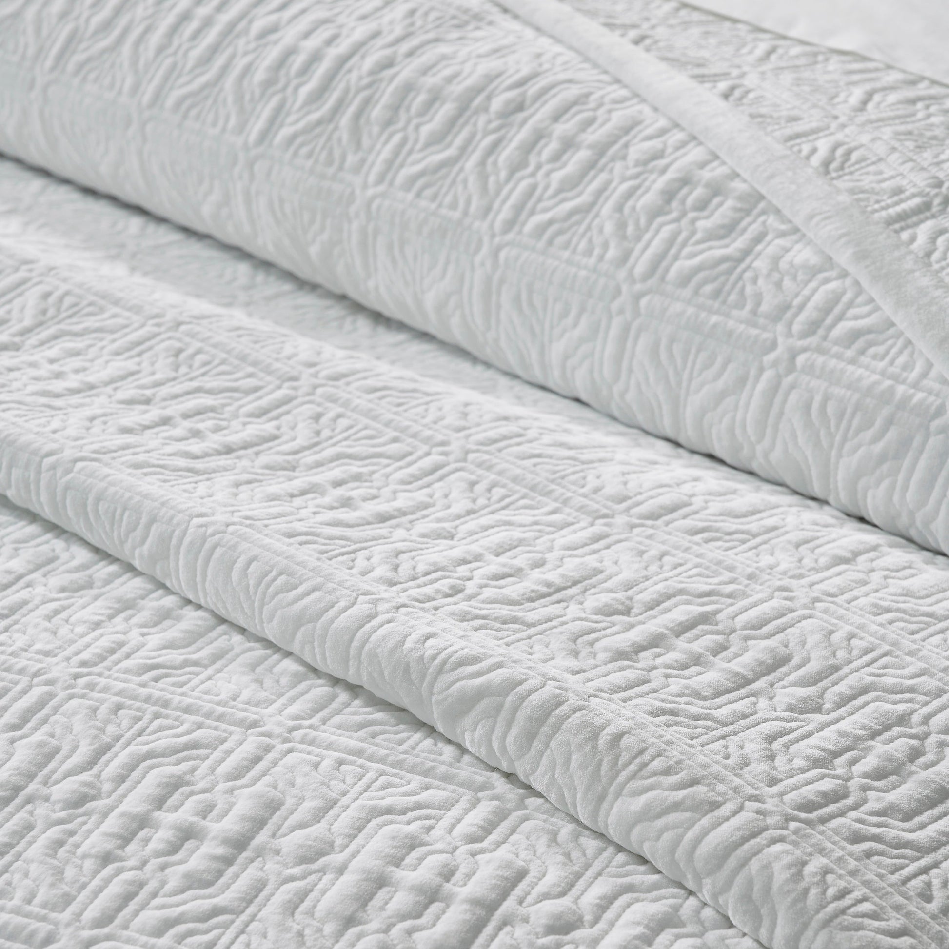 QT-376-9496_6|Folded layers of white quilted fabric, intricate geometric pattern. Luxurious textured quilt, perfect for cozy and elegant bedding.