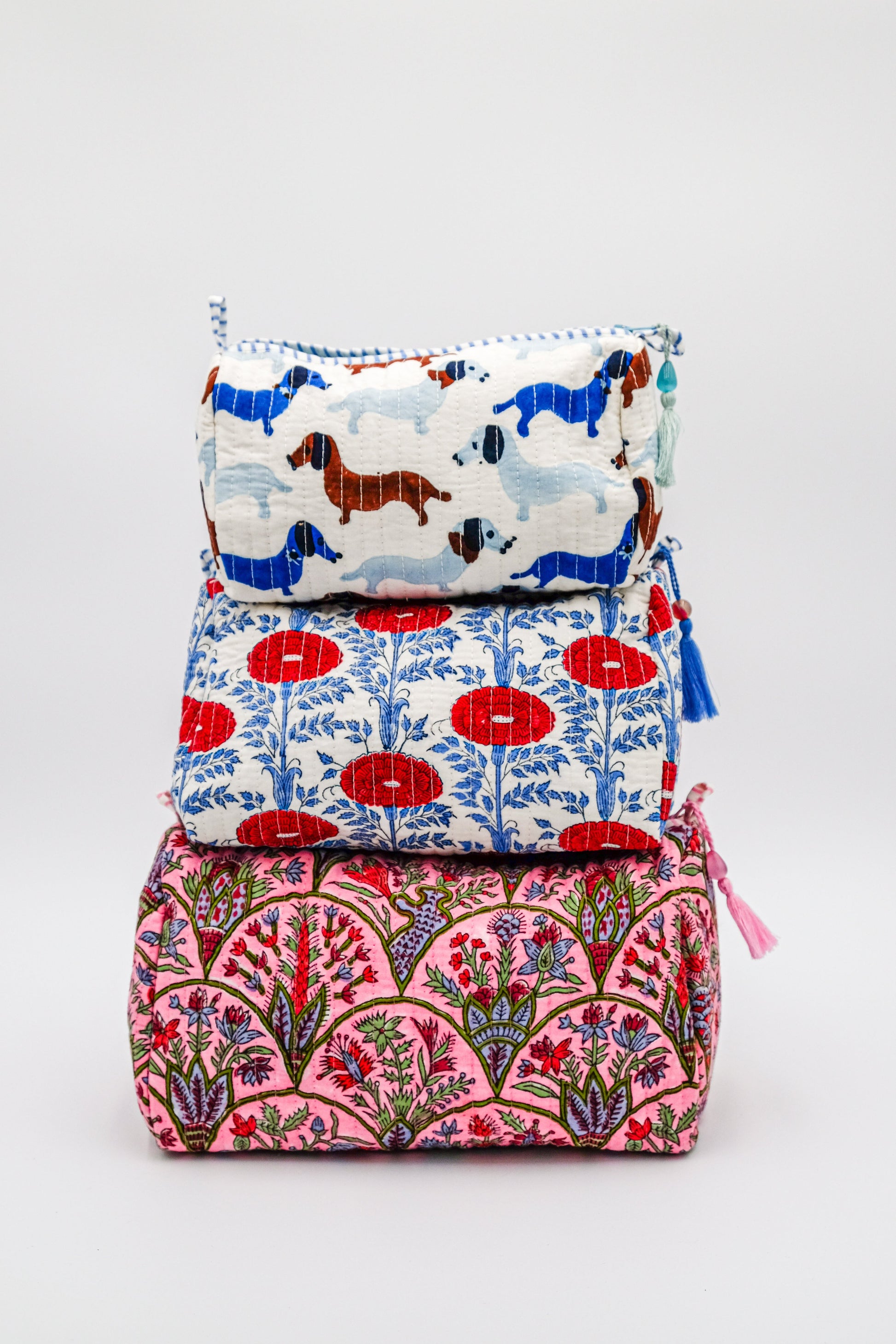 Stacked toiletry bags with colorful patterns including dog prints and floral designs from Inner Child