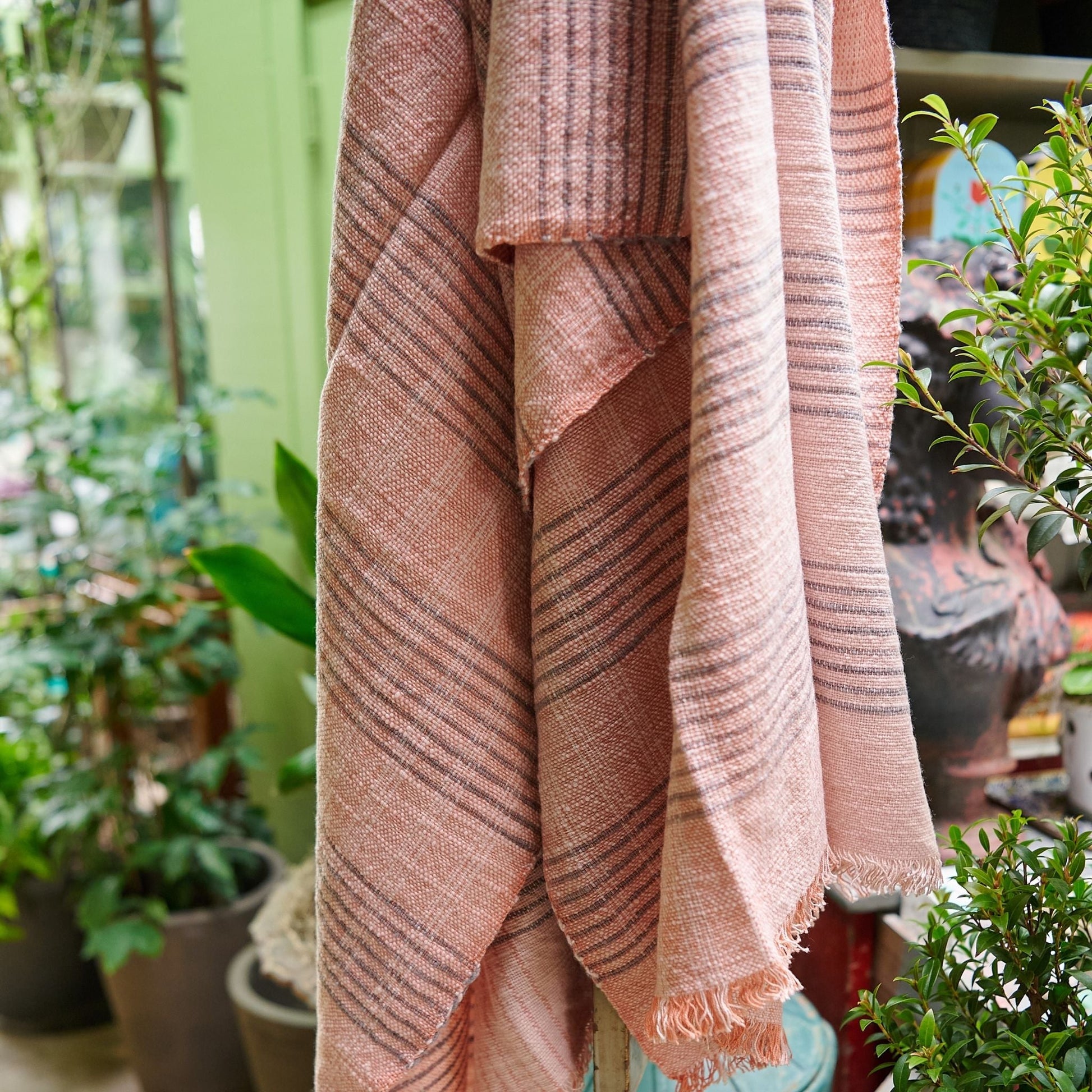 Silica Rose In Shades of Salmon Pink Gray Stripes Pattern Soft Handwoven Merino Throw hanging in a floral decor setting.
