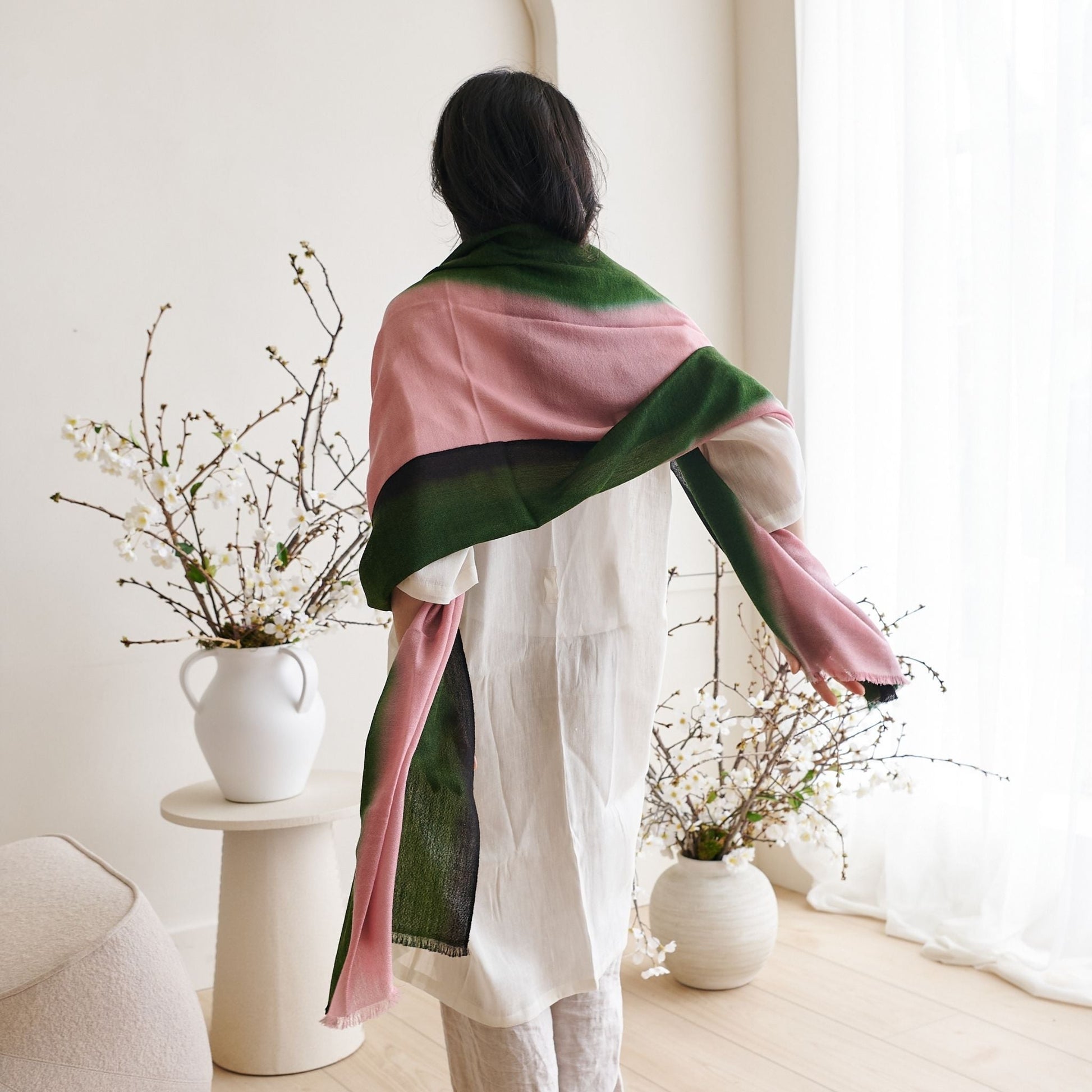 Model showcasing the Iris Kiwi Green Pink Cashmere Merino Handwoven Scarf elegantly styled with floral decor.
