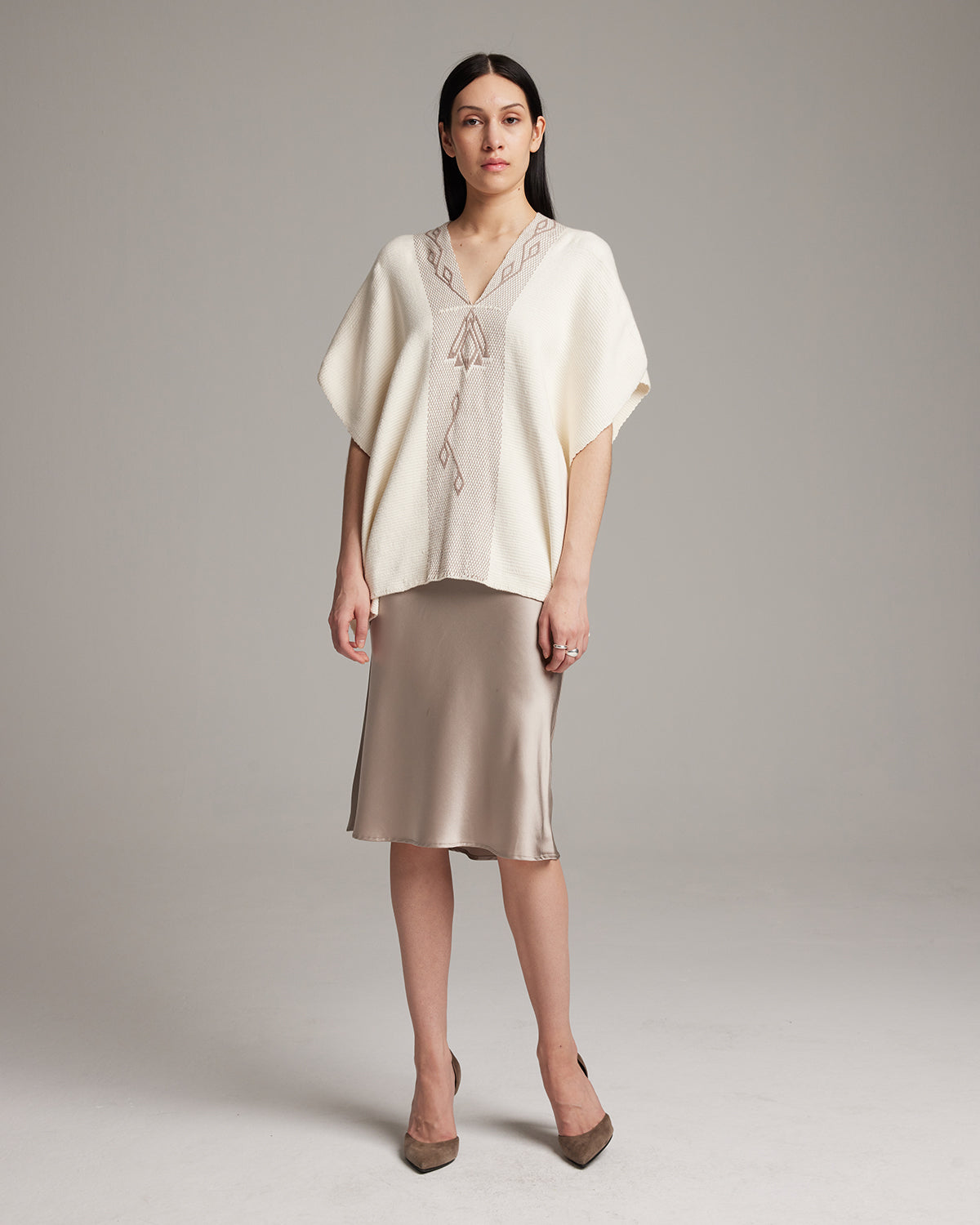 Model wearing a Copihue Manta in ivory with geometric embroidery