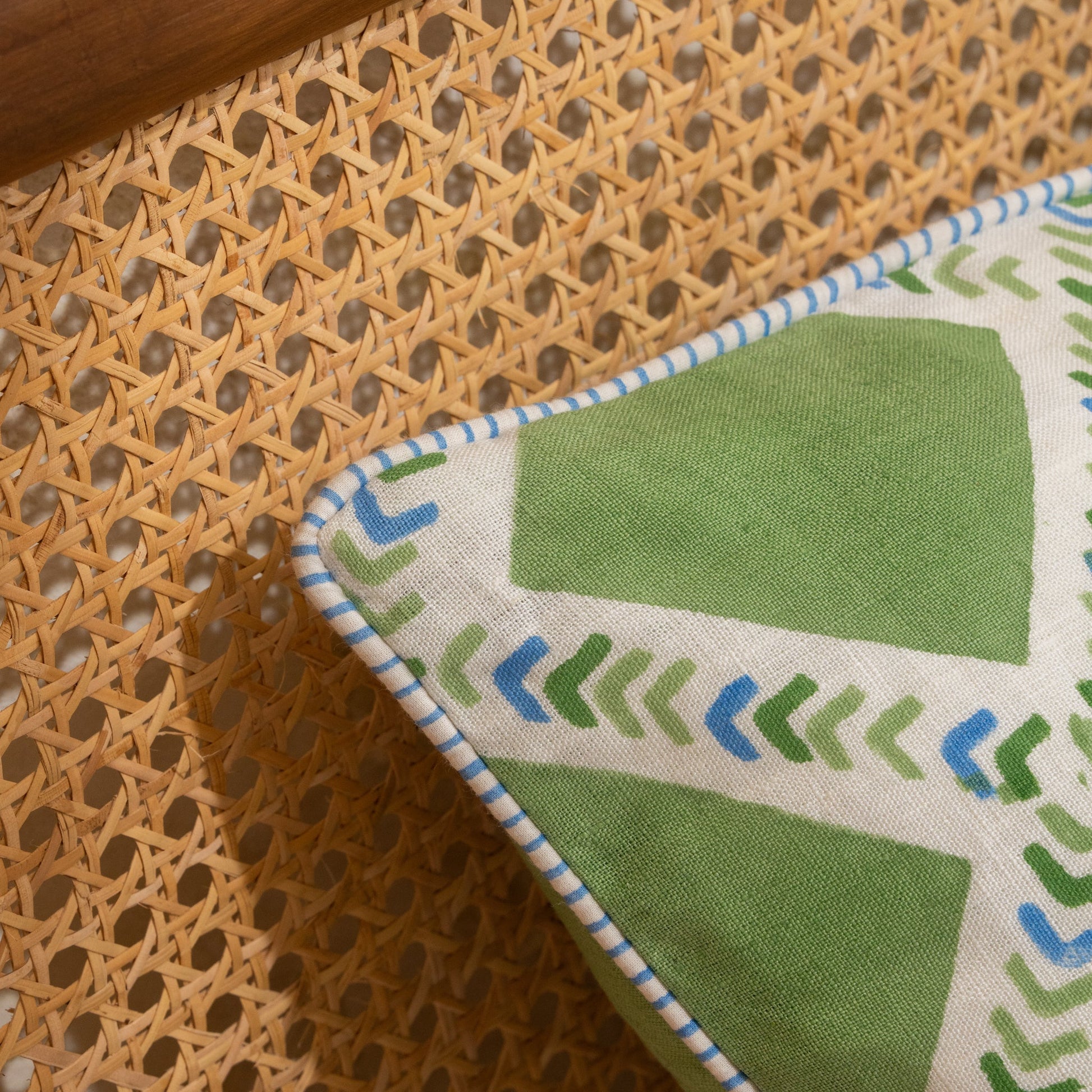 Hand block printed linen pillow cover with interlocking geometric green and blue chevron  print in natural dyes placed on a woven surface