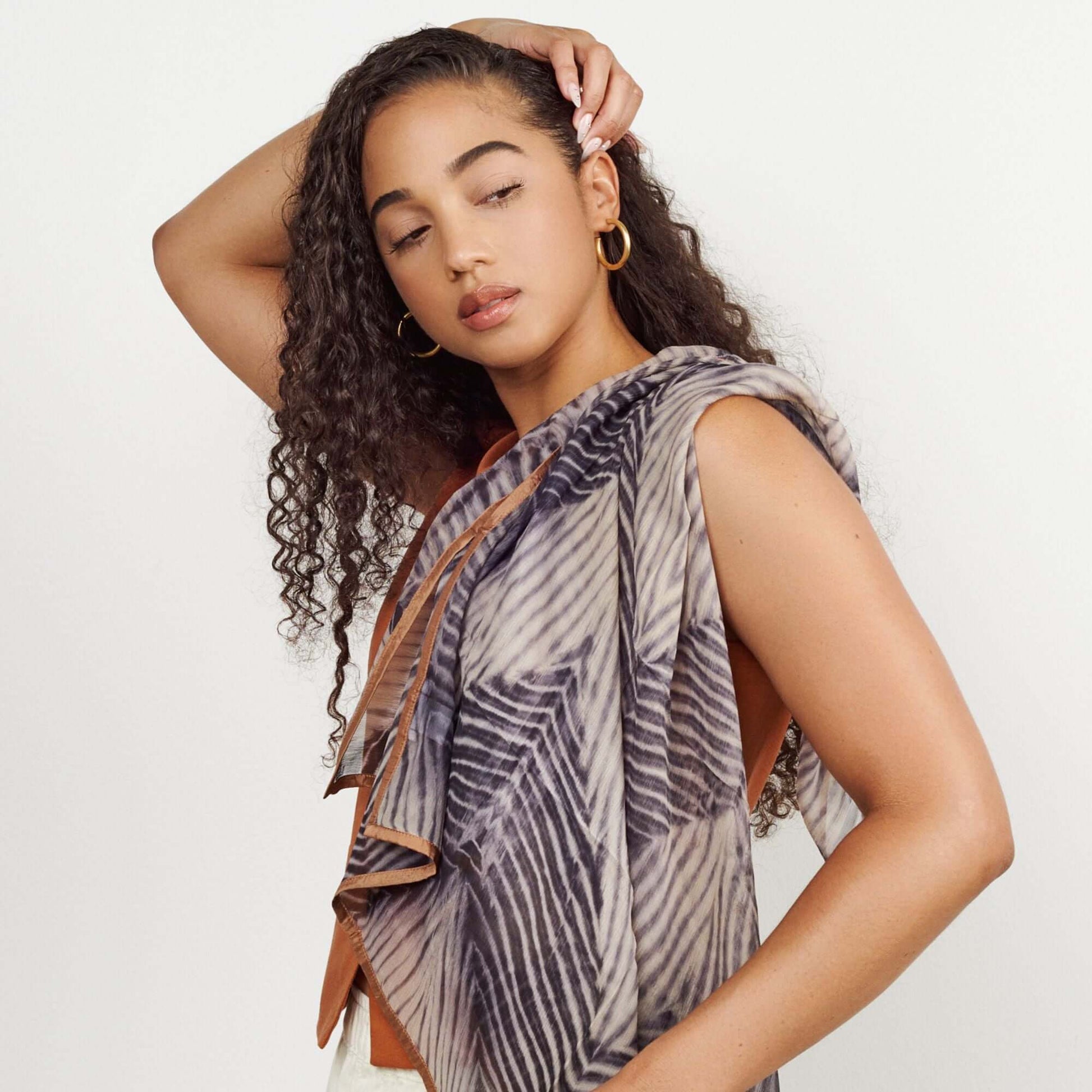 Chiffon square scarf Samu Black styled elegantly by a model with curly hair, showcasing its unique Shibori print design.