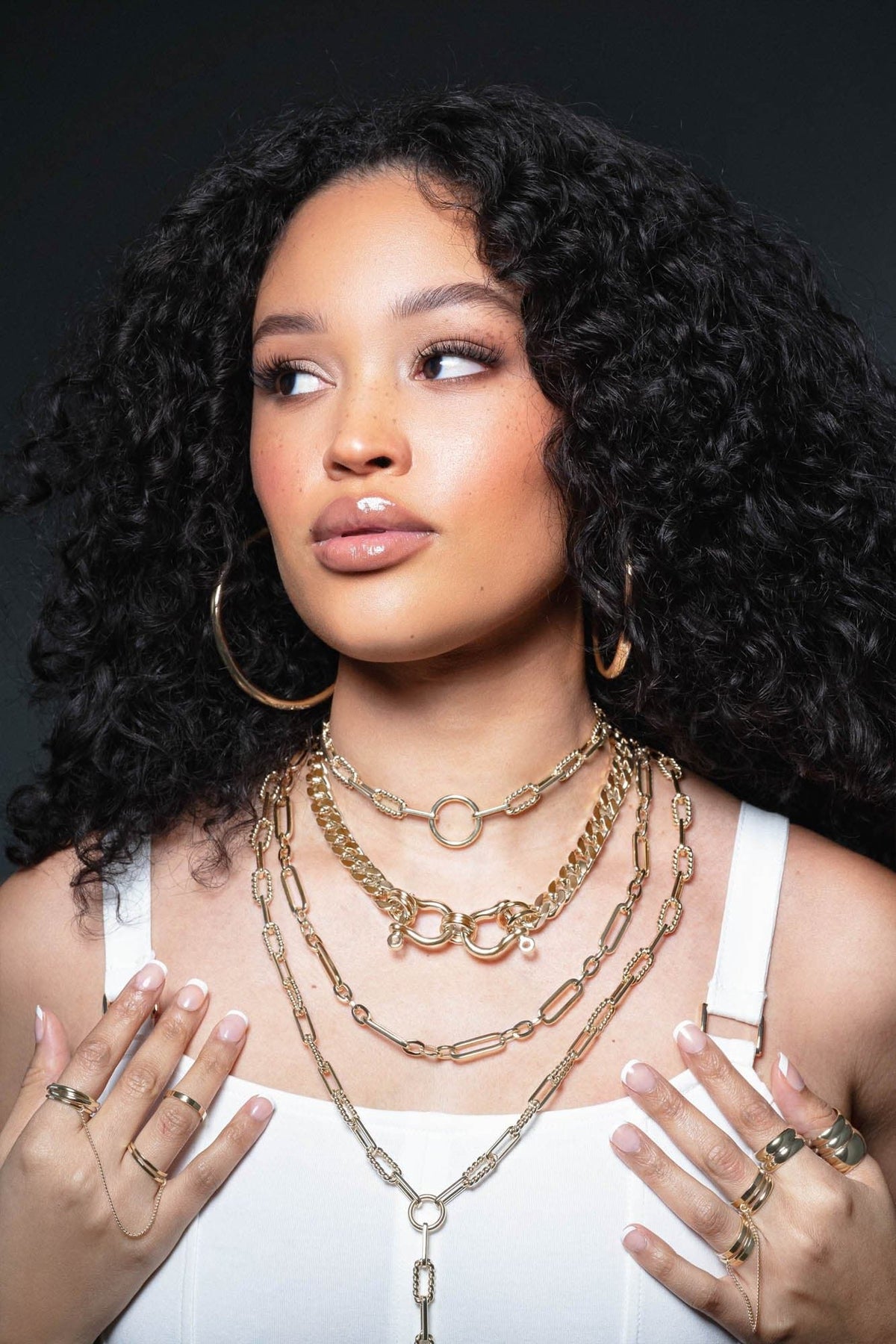 Woman wearing multiple gold necklaces and rings, showing off the Skye Necklace stylishly