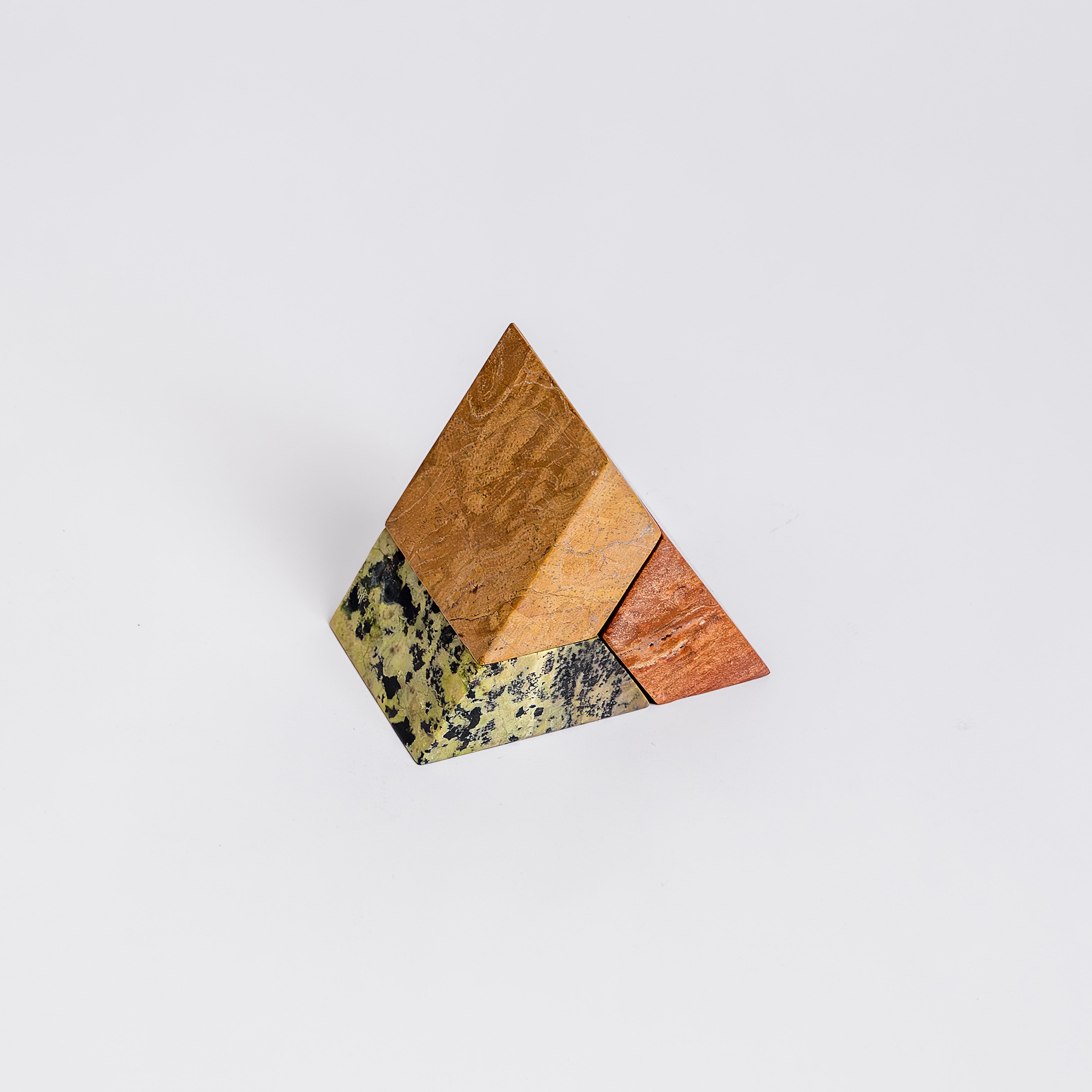 Frontal view showcasing the distinct individual blocks of the green, orange, and cream triangle puzzle candelabra, highlighting its architectural silhouette.