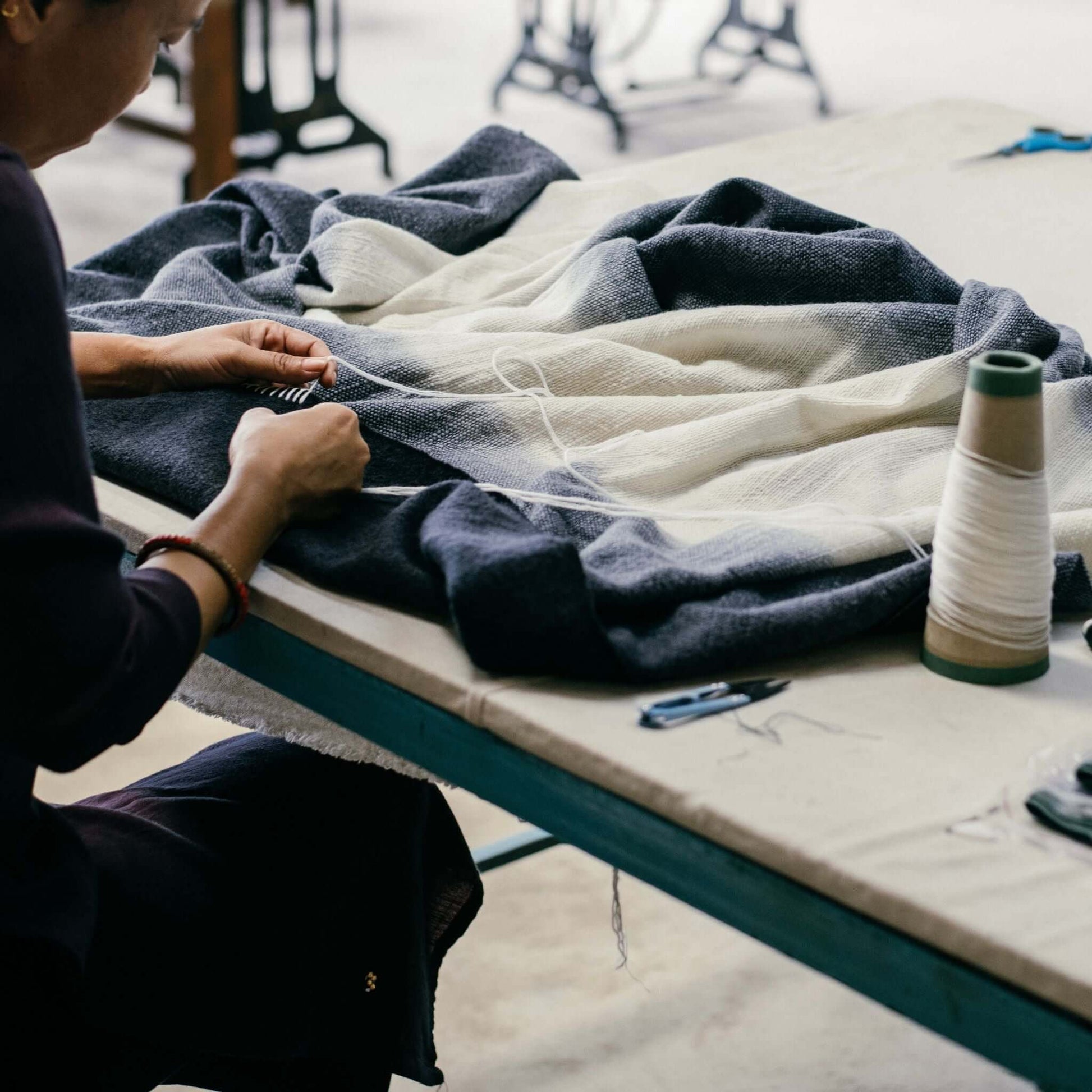 Artisan stitching the Ink Black White Ombre Textured Throw In Hand Spun Merino And Hand Stitched Hem.
