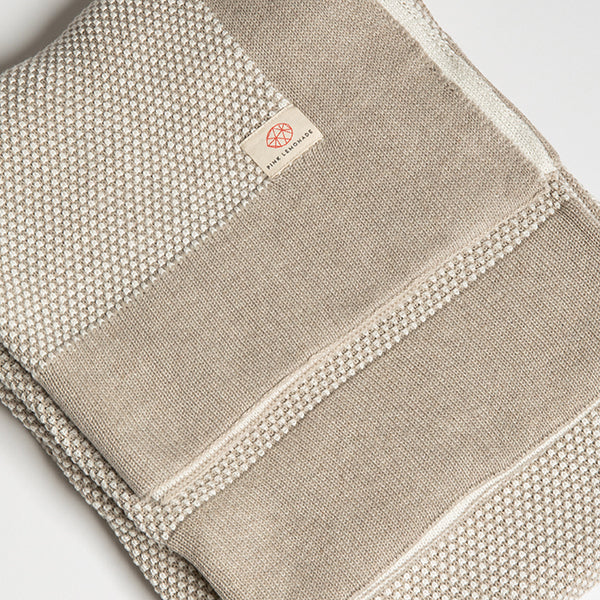 Folded beige throw blanket with a solid border and a Pink Lemonade brand label.