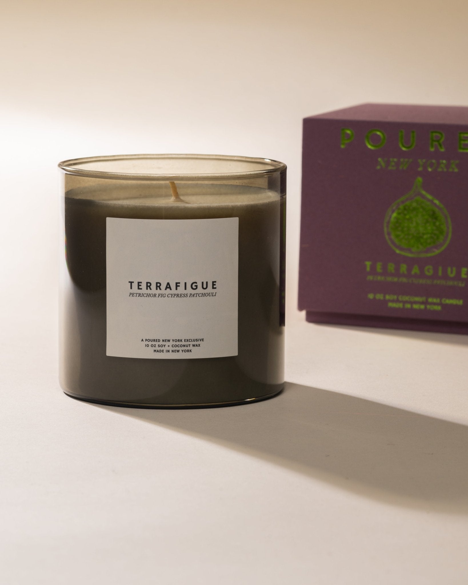 Poured New York 'Terrafigue' candle with a purple box in the background with a fig decal on a light background