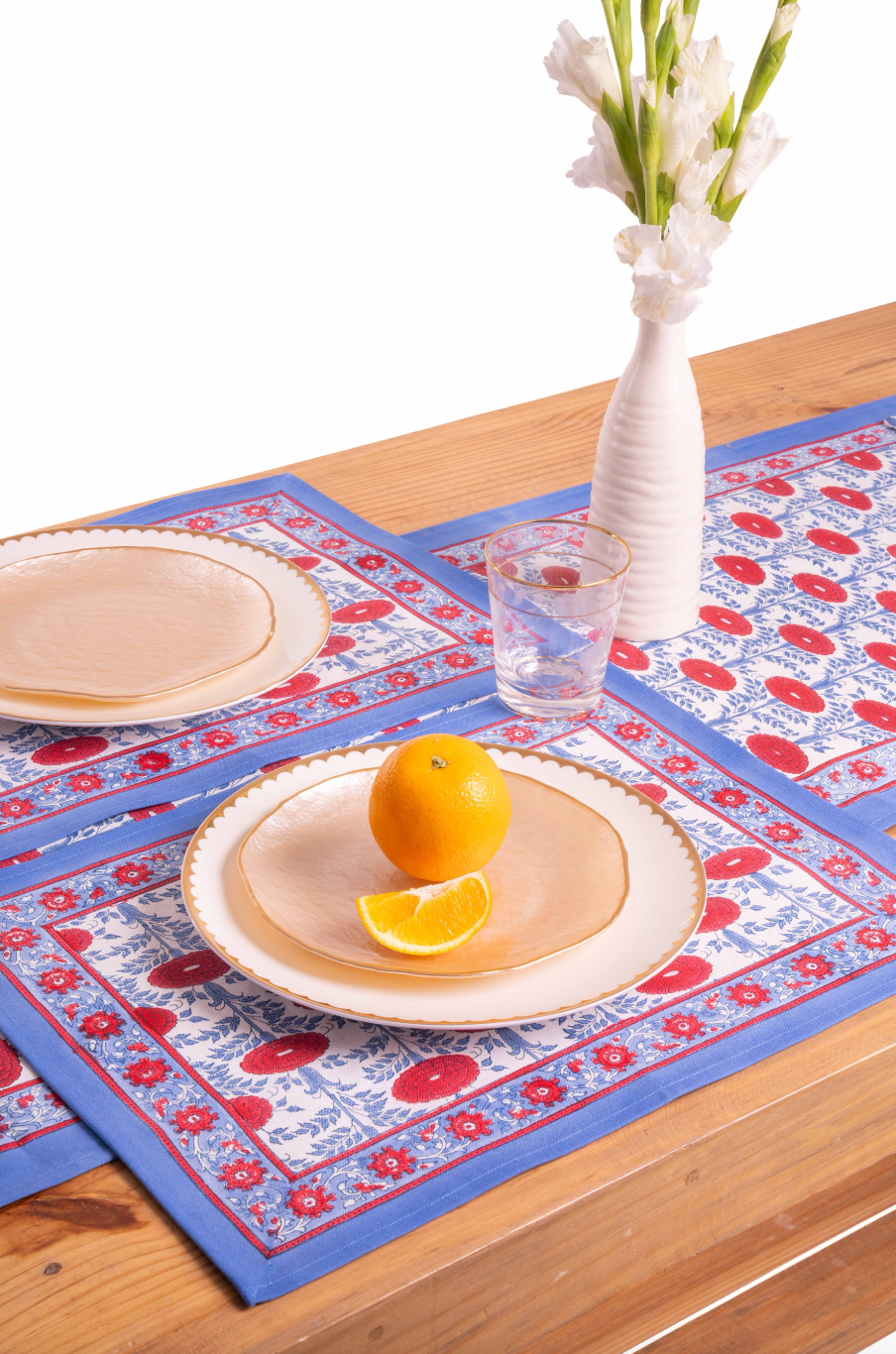Inner Child Araminta Blockprint placemat with blue/red floral pattern, wooden table with orange and plates