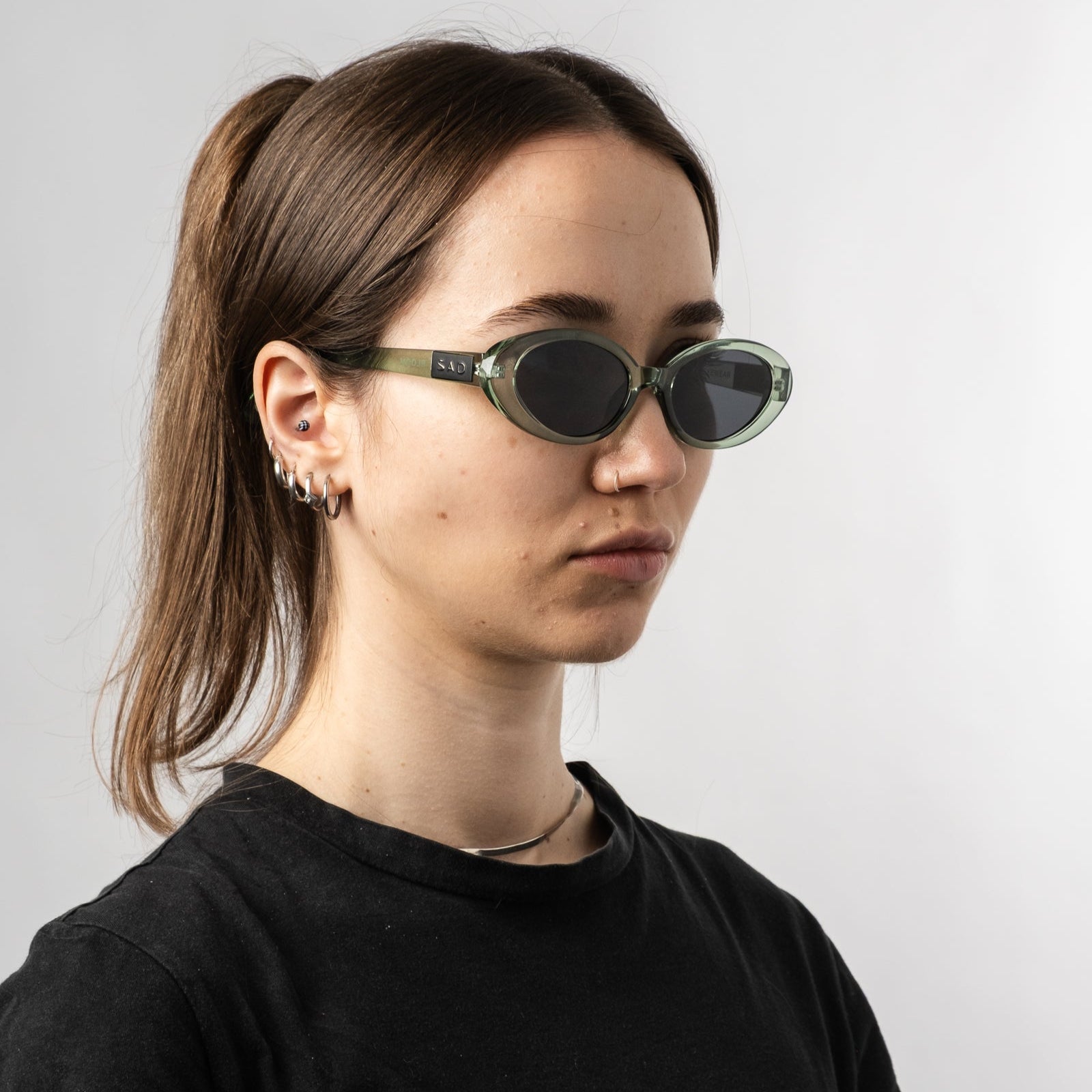 Female wearing Sad Eyewear Bloom oval sunglasses in sea glass green with tinted black lenses