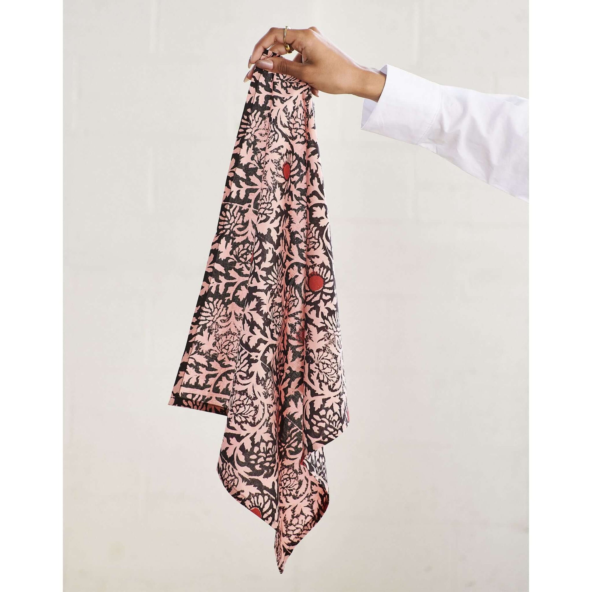 Hummus Floral Wax Block Printe Cotton Table Napkin( set of 4 ) held by hand, showcasing intricate black and red block print design.